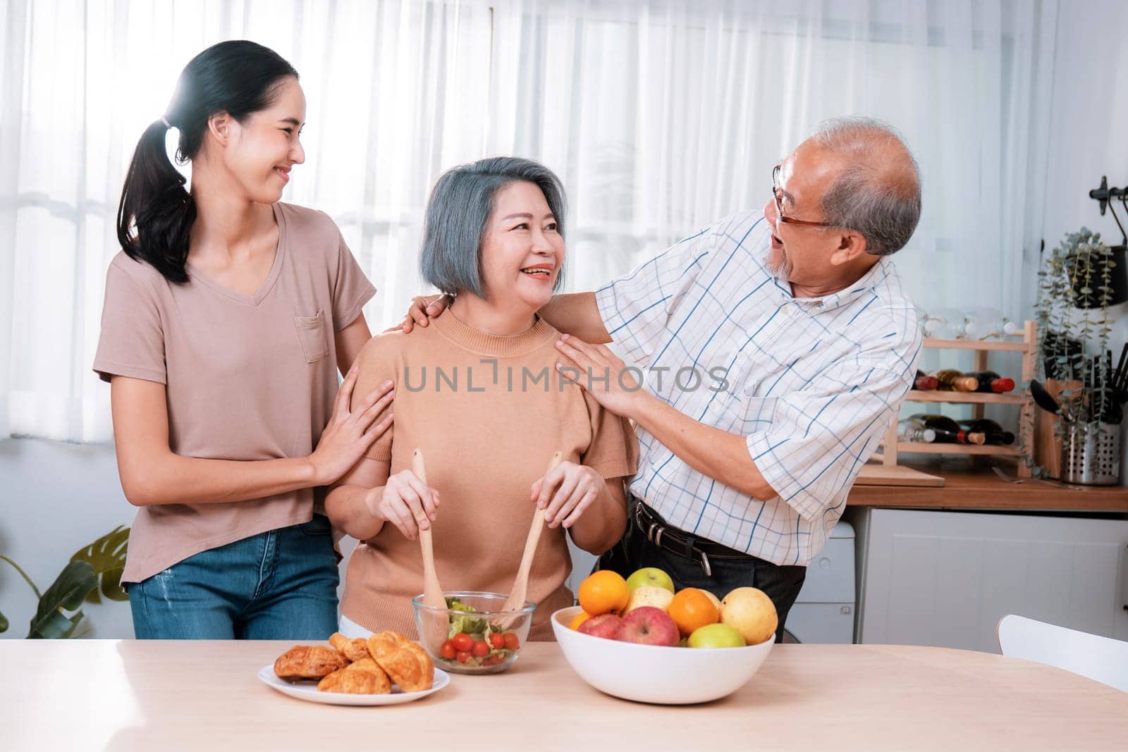 Contented family, daughter, father, mother prepare bread veggies and fruit salad together in their kitchen.