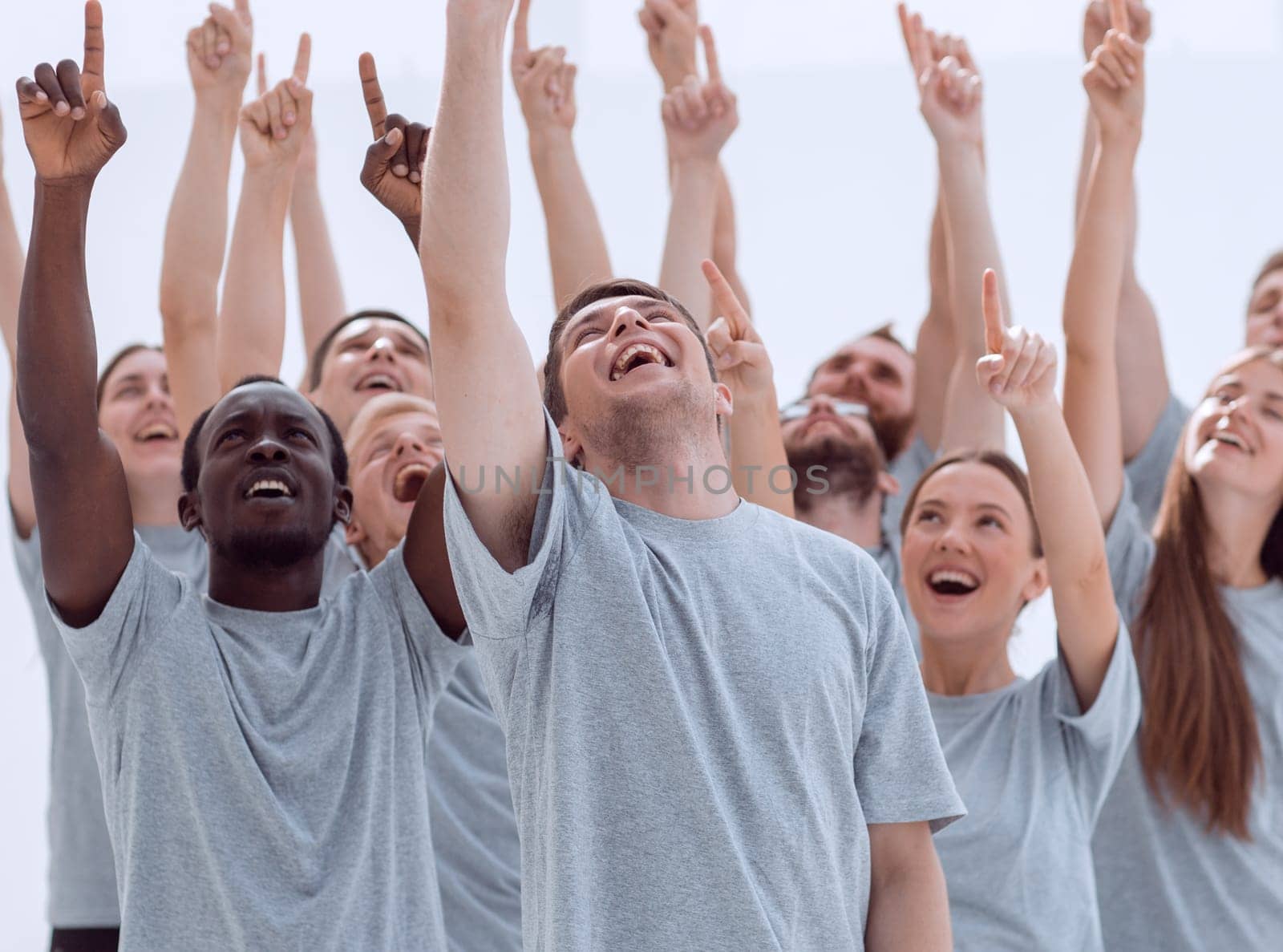 close up. a team of happy young people pointing upwards. by asdf