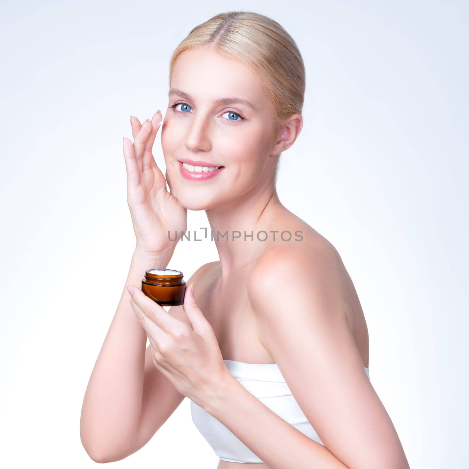 Closeup personable woman applying moisturizer cream on her face for perfect ski by biancoblue