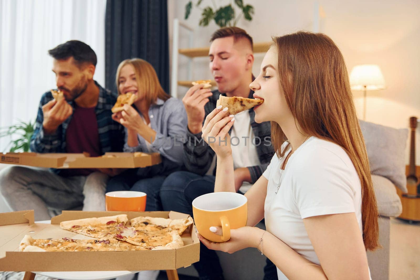It's pizza time. Group of friends have party indoors together.