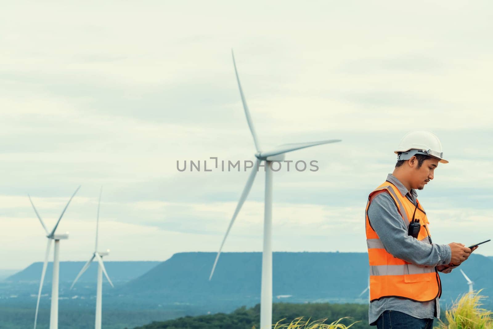 Engineer working on a wind farm atop a hill or mountain in the rural. Progressive ideal for the future production of renewable, sustainable energy. Energy generation from wind turbine.