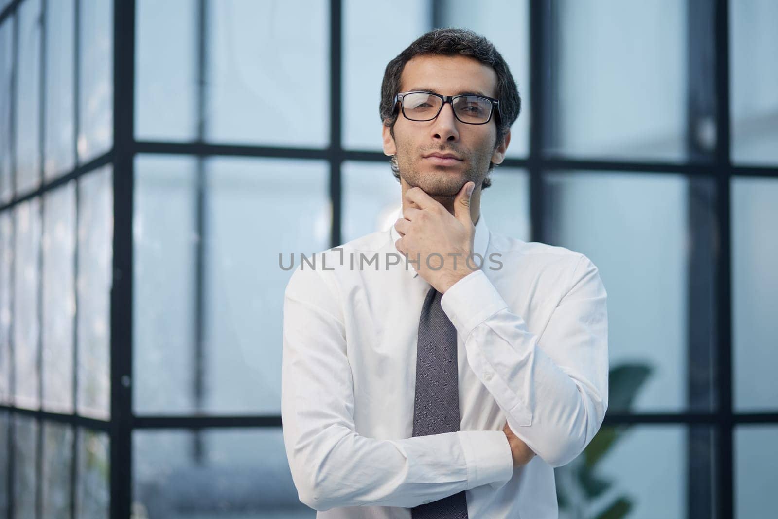 Thinking about business. Thoughtful young man in formalwear looking at camera while holding hand on chin