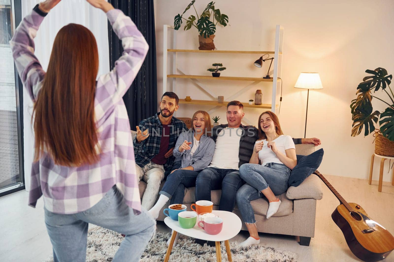Playing game with using body language and poses. Group of friends have party indoors together.