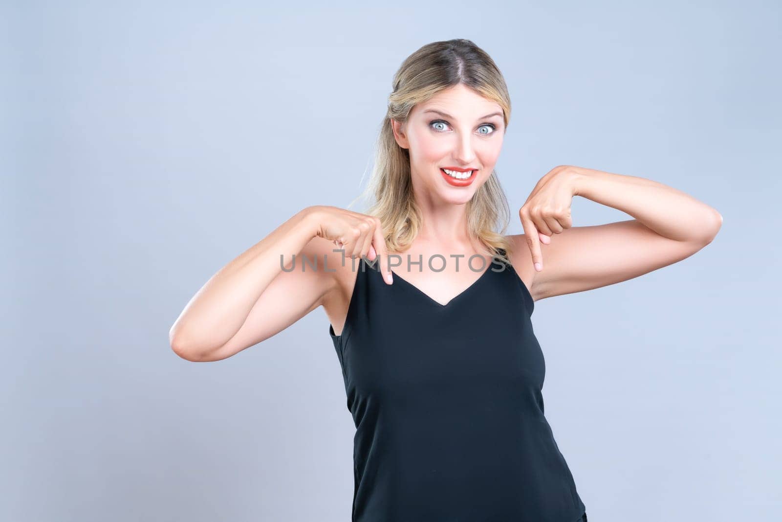 Alluring beautiful woman pointing finger down in isolated background by biancoblue
