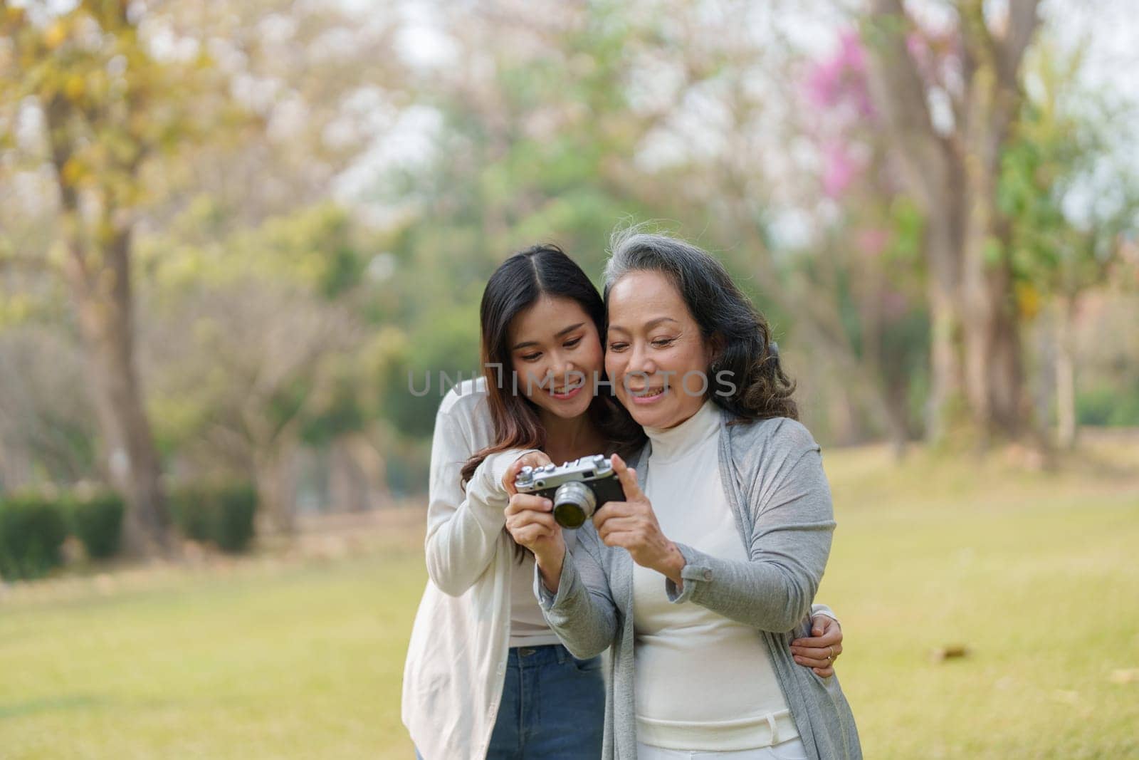 Asian teenage mother and daughter walking in park with camera to capture memories by Manastrong