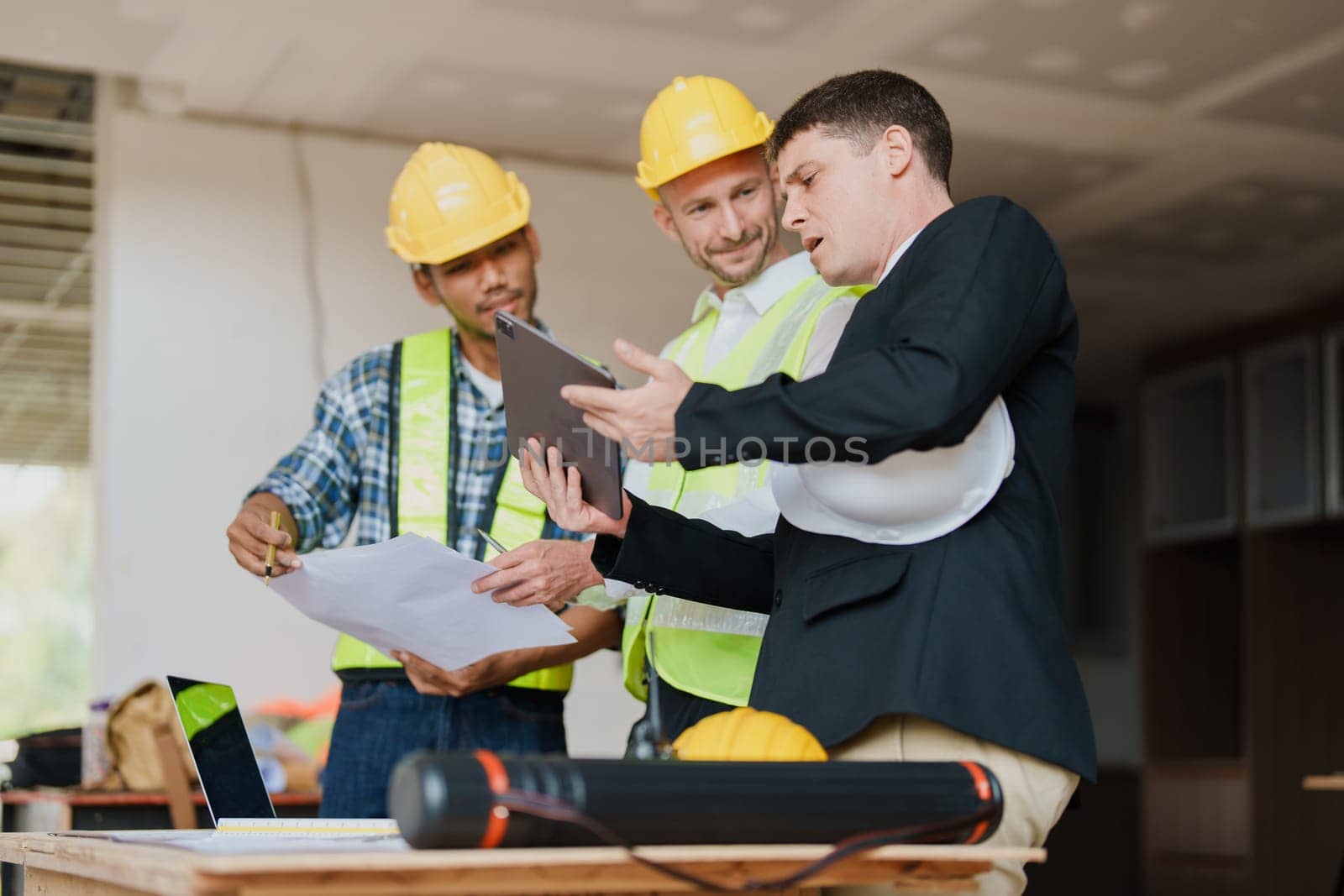 multi ethnic engineer brainstorming and measuring for cost estimating on paperworks and floor plan drawings about design architectural and engineering for houses and buildings.