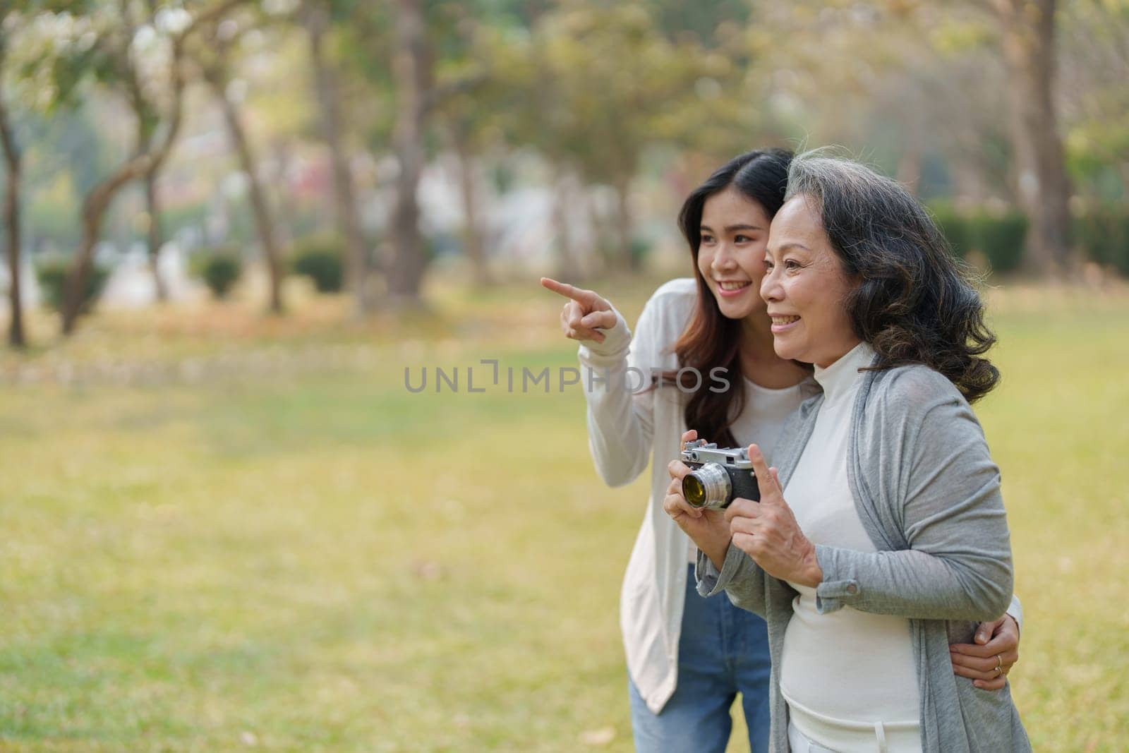 Asian teenage mother and daughter walking in park with camera to capture memories.