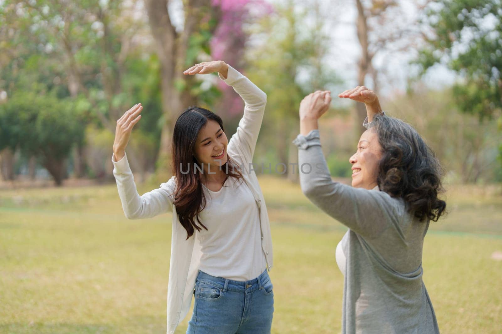 Grown daughter with aging mother showing love and walking together in the parkland by Manastrong