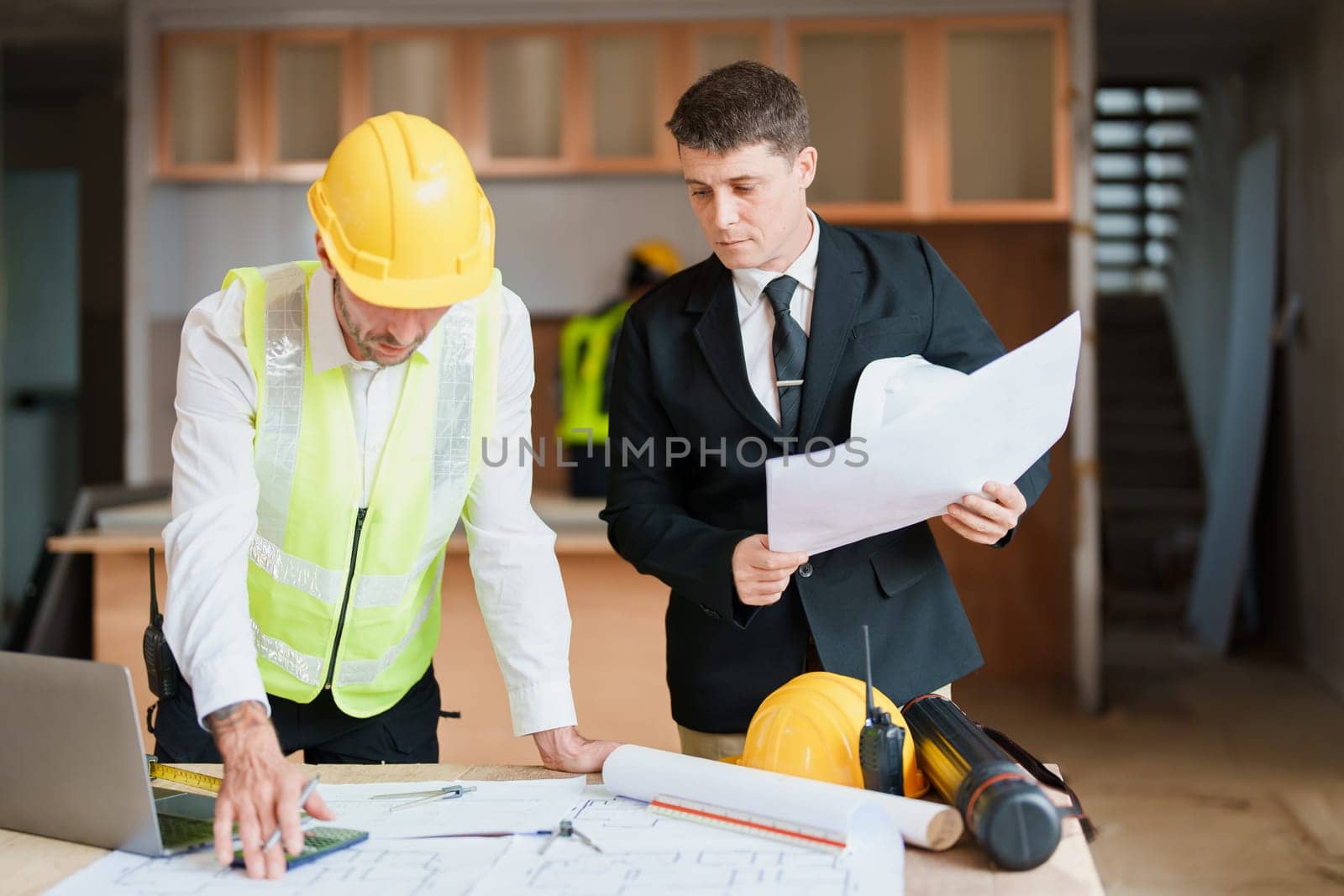 multi ethnic engineer brainstorming and measuring for cost estimating on blueprint and floor plan drawings about design architectural and engineering for houses and buildings by Manastrong