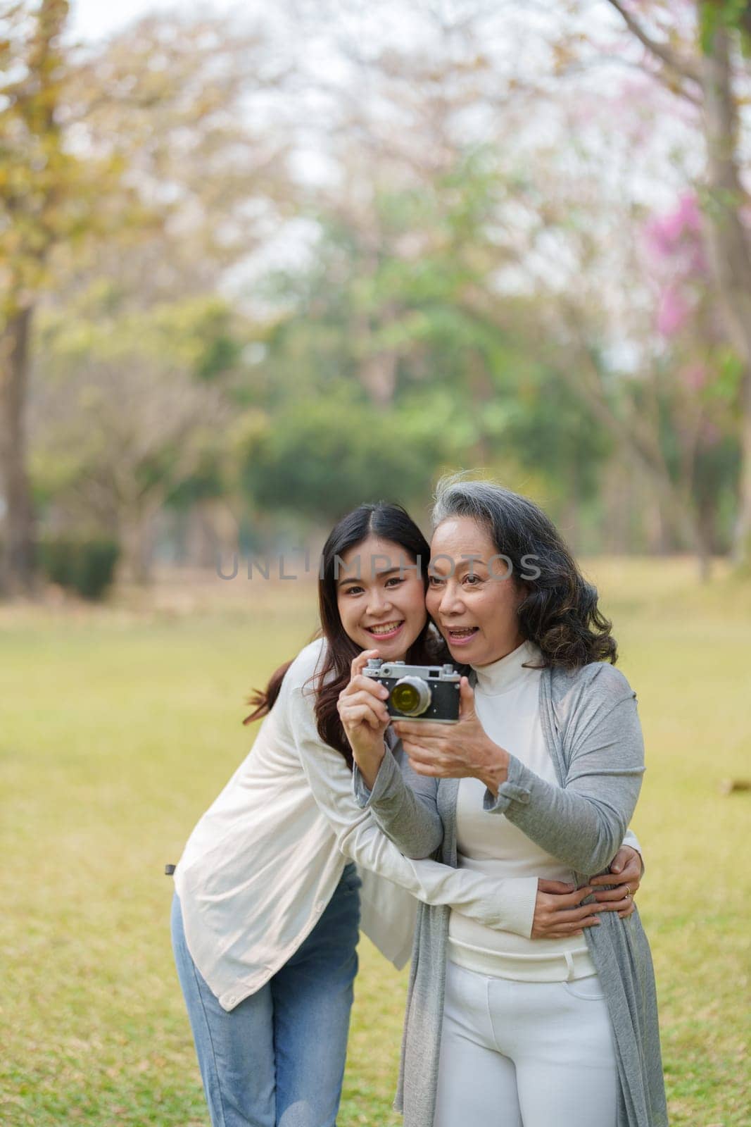 Asian teenage mother and daughter walking in park with camera to capture memories.