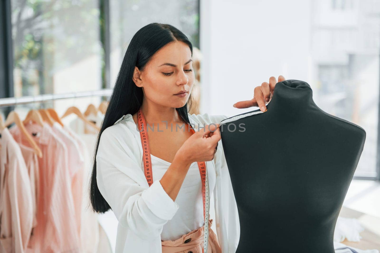 Measuring clothes. Seamstress is in her office.