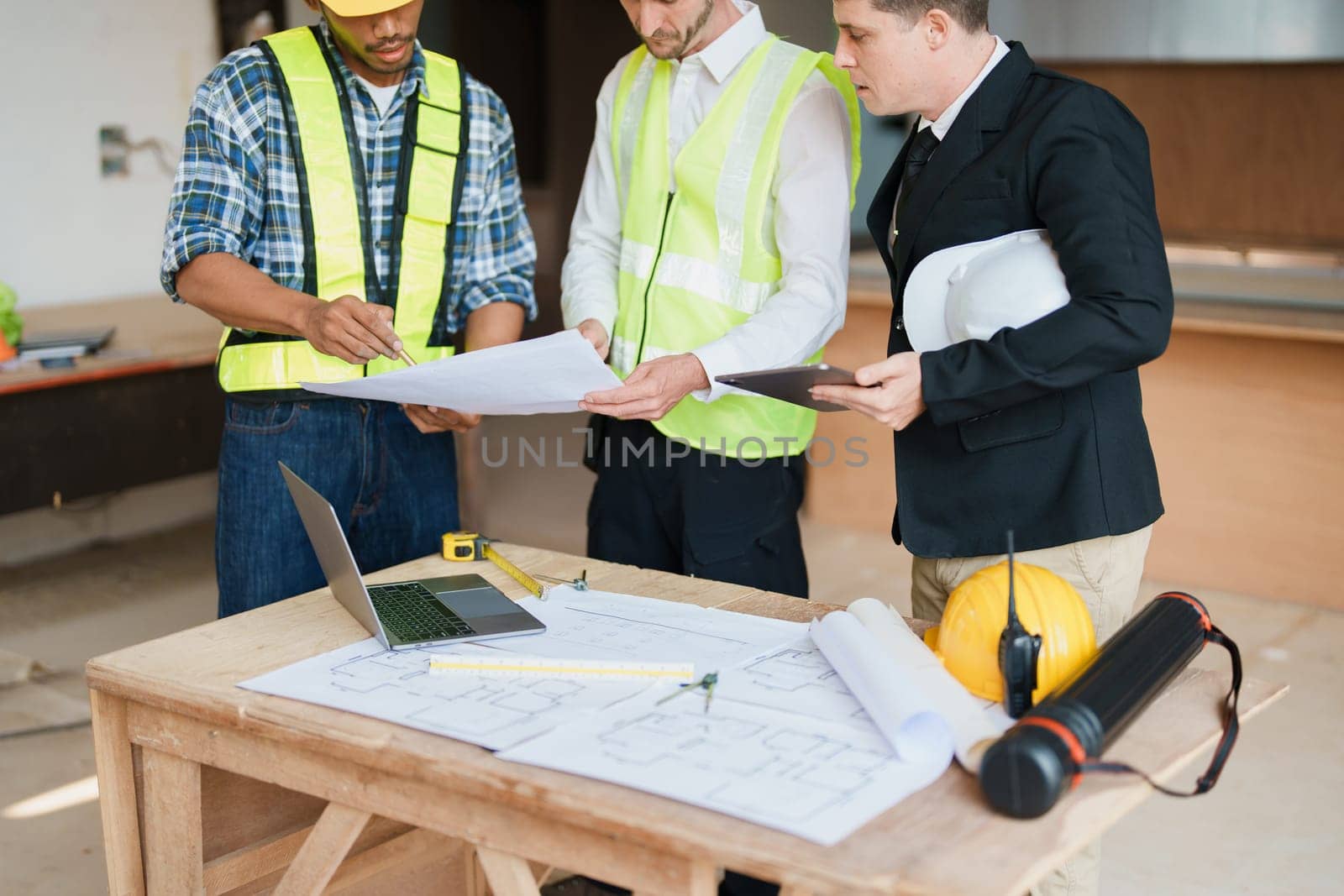 multi ethnic engineer brainstorming and measuring for cost estimating on paperworks and floor plan drawings about design architectural and engineering for houses and buildings.