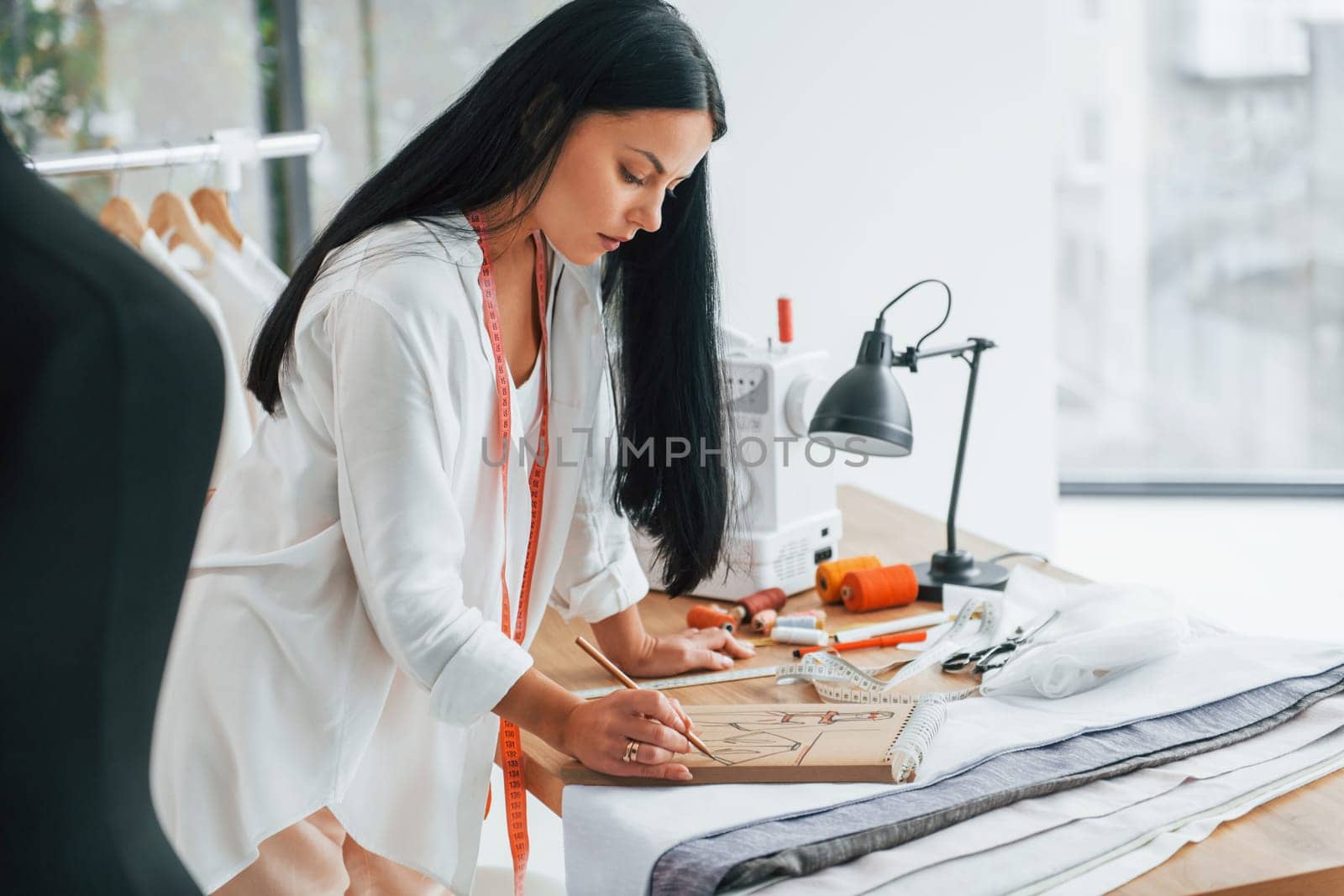 Working with precision. Seamstress is in her office that is with different clothes.