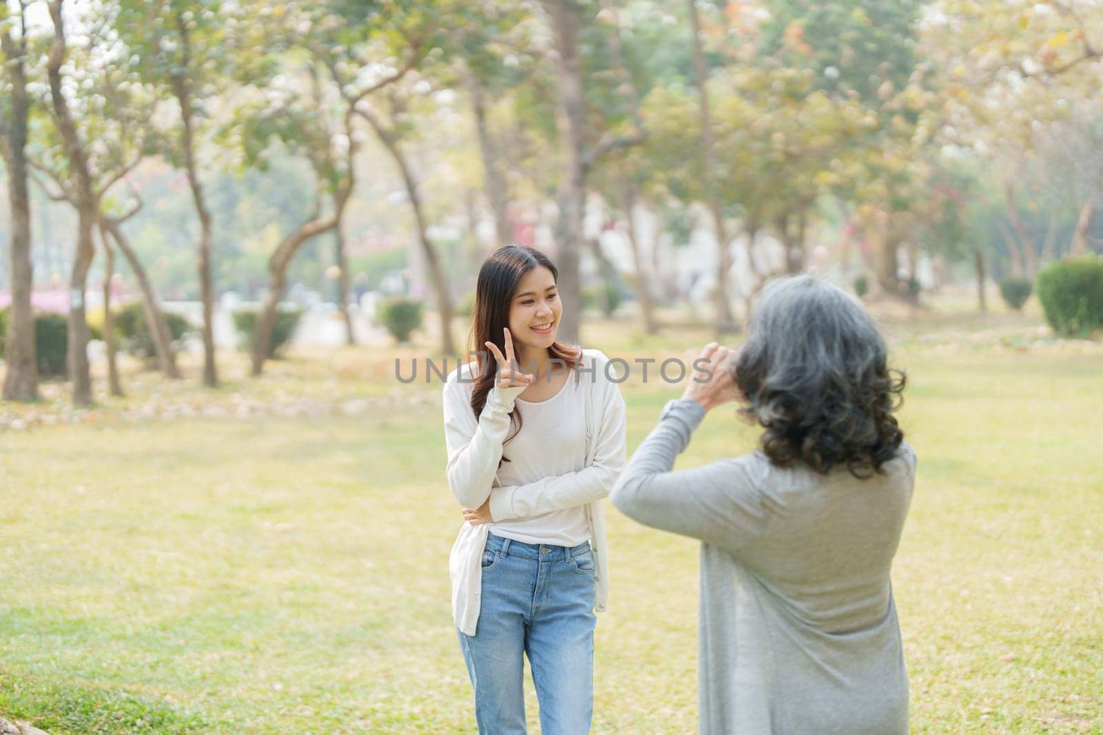 Asian teenage mother and daughter walking in park with camera to capture memories.