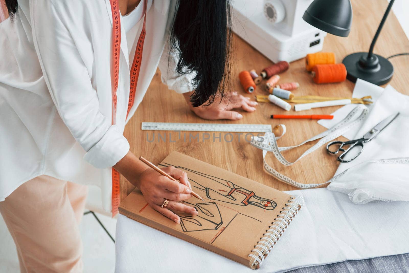 Working with precision. Seamstress is in her office that is with different clothes.