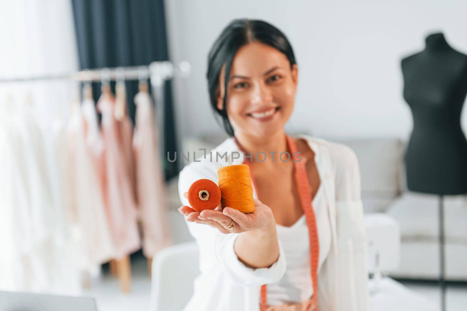 Standing and posing. Seamstress is in her office that is with different clothes.