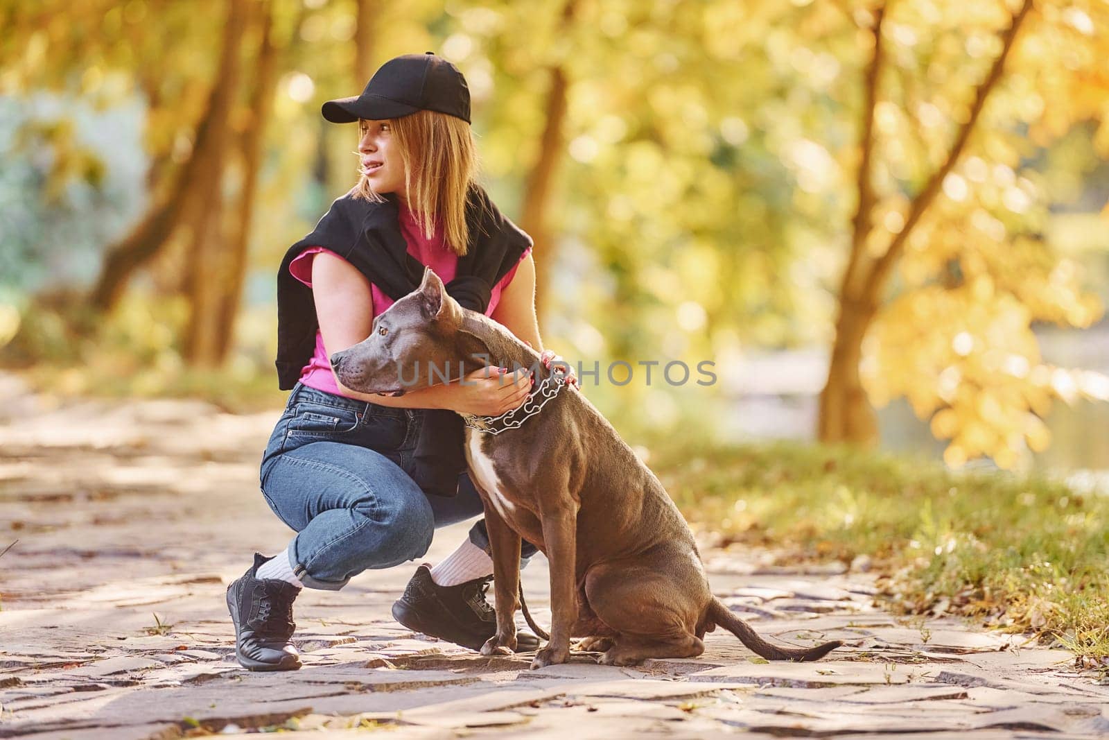 Having fun. Woman in casual clothes is with pit bull outdoors.