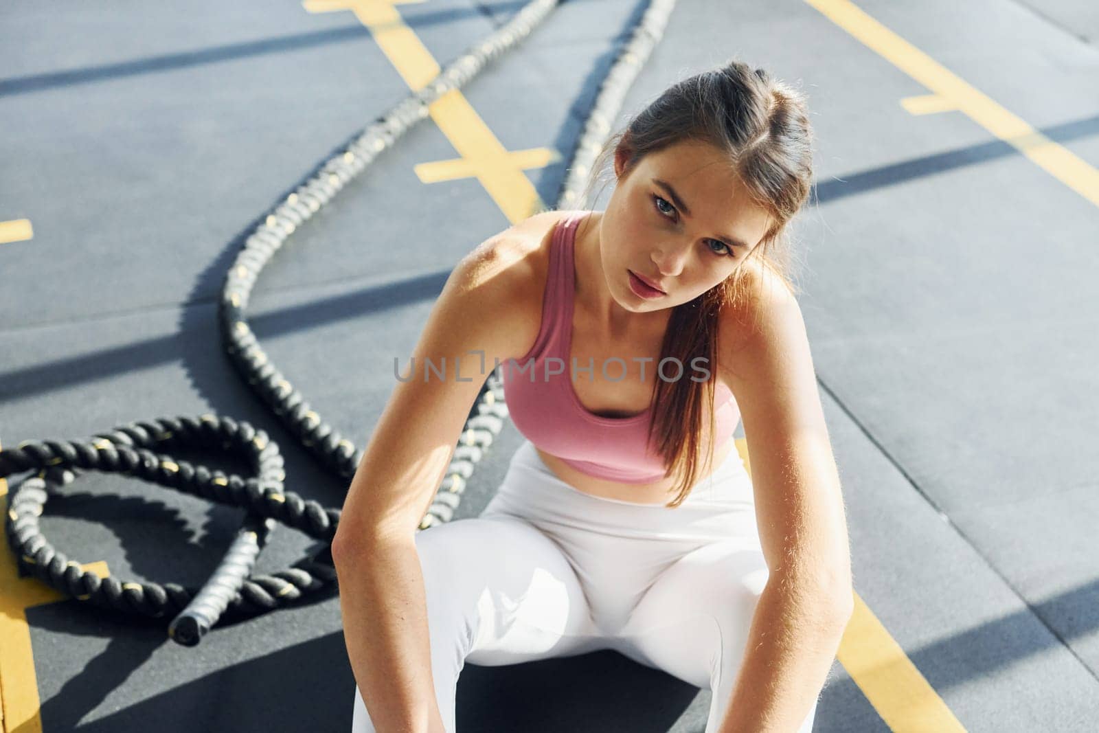 Sitting on the ground. Beautiful young woman with slim body type is in the gym.