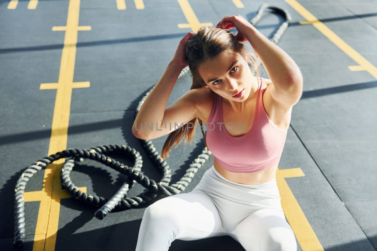Sitting on the ground. Beautiful young woman with slim body type is in the gym.