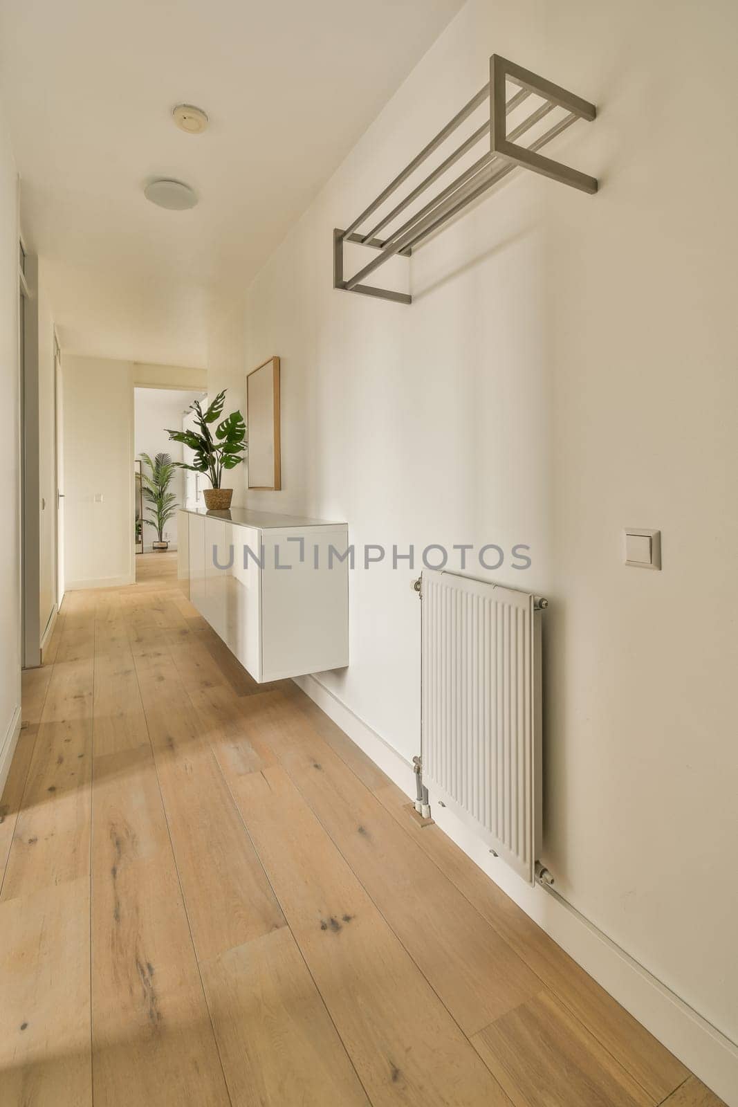 a long white hallway with wood floors and white furniture by casamedia