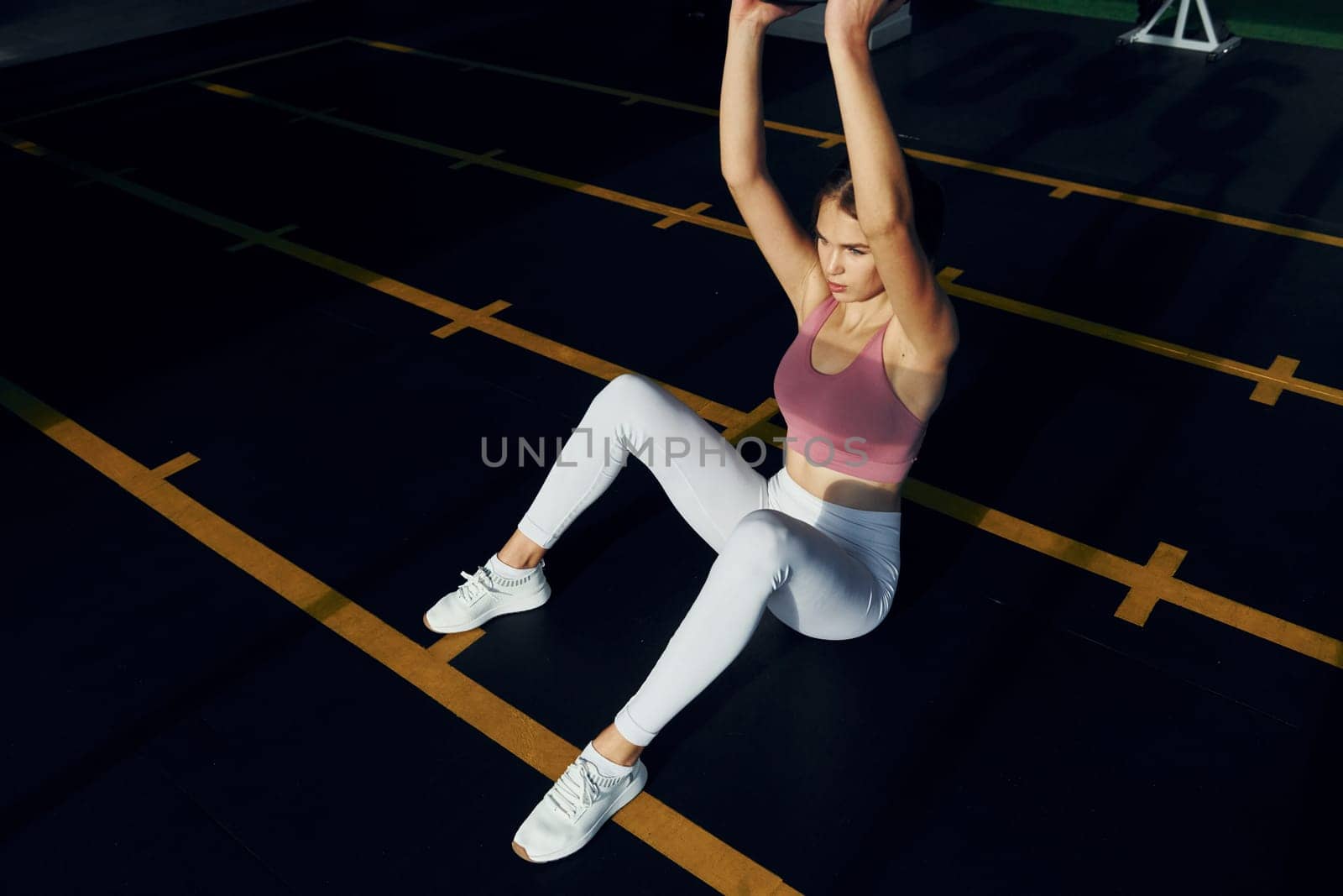 Holding weight in hands. Beautiful young woman with slim body type is in the gym.