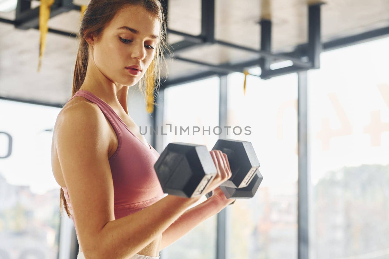 Focused on exercise. Beautiful young woman with slim body type is in the gym.