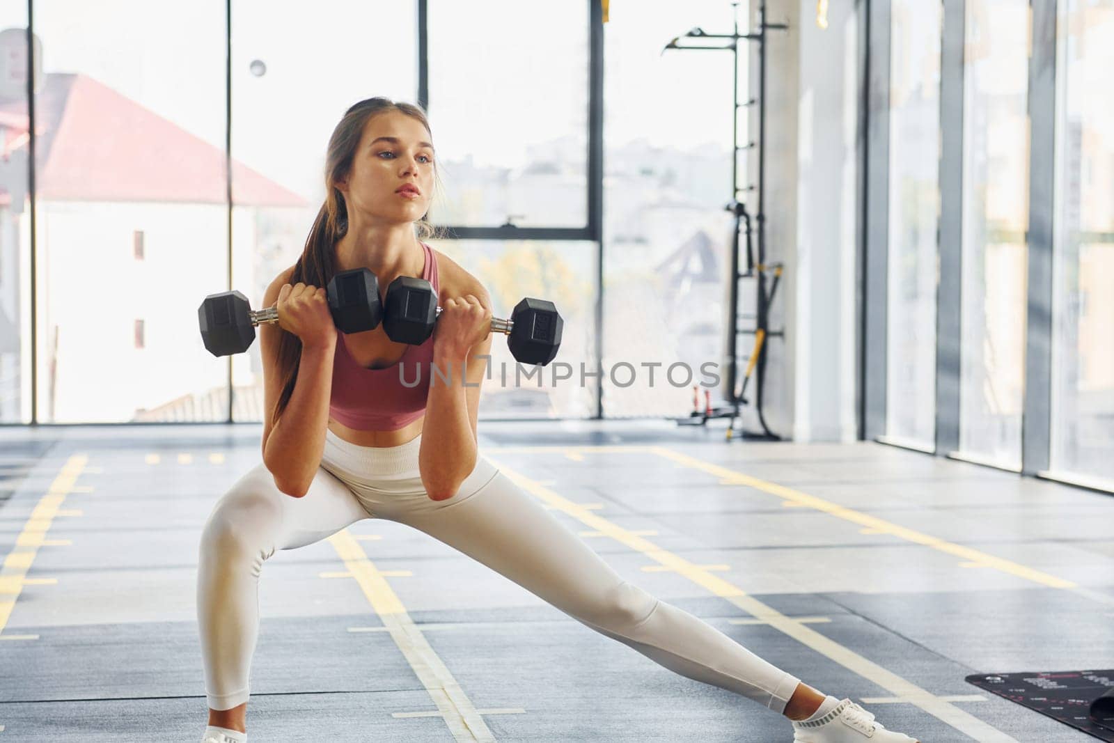 Focused on exercise. Beautiful young woman with slim body type is in the gym.