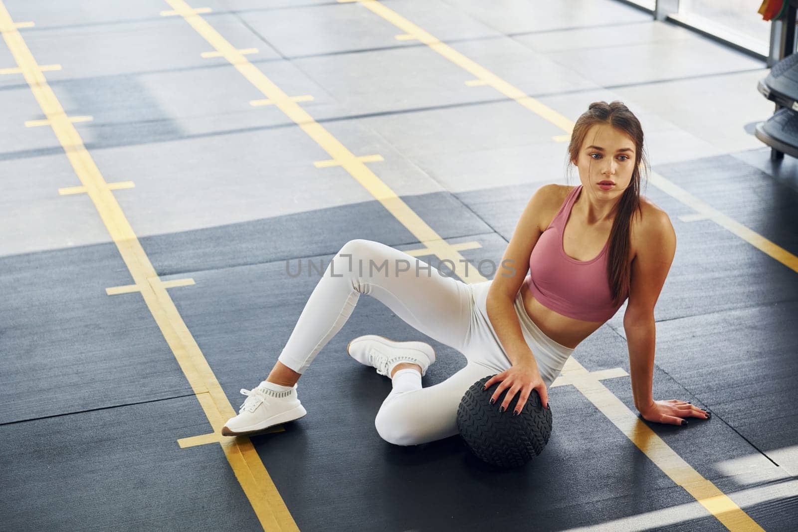 In white pants. Beautiful young woman with slim body type is in the gym.