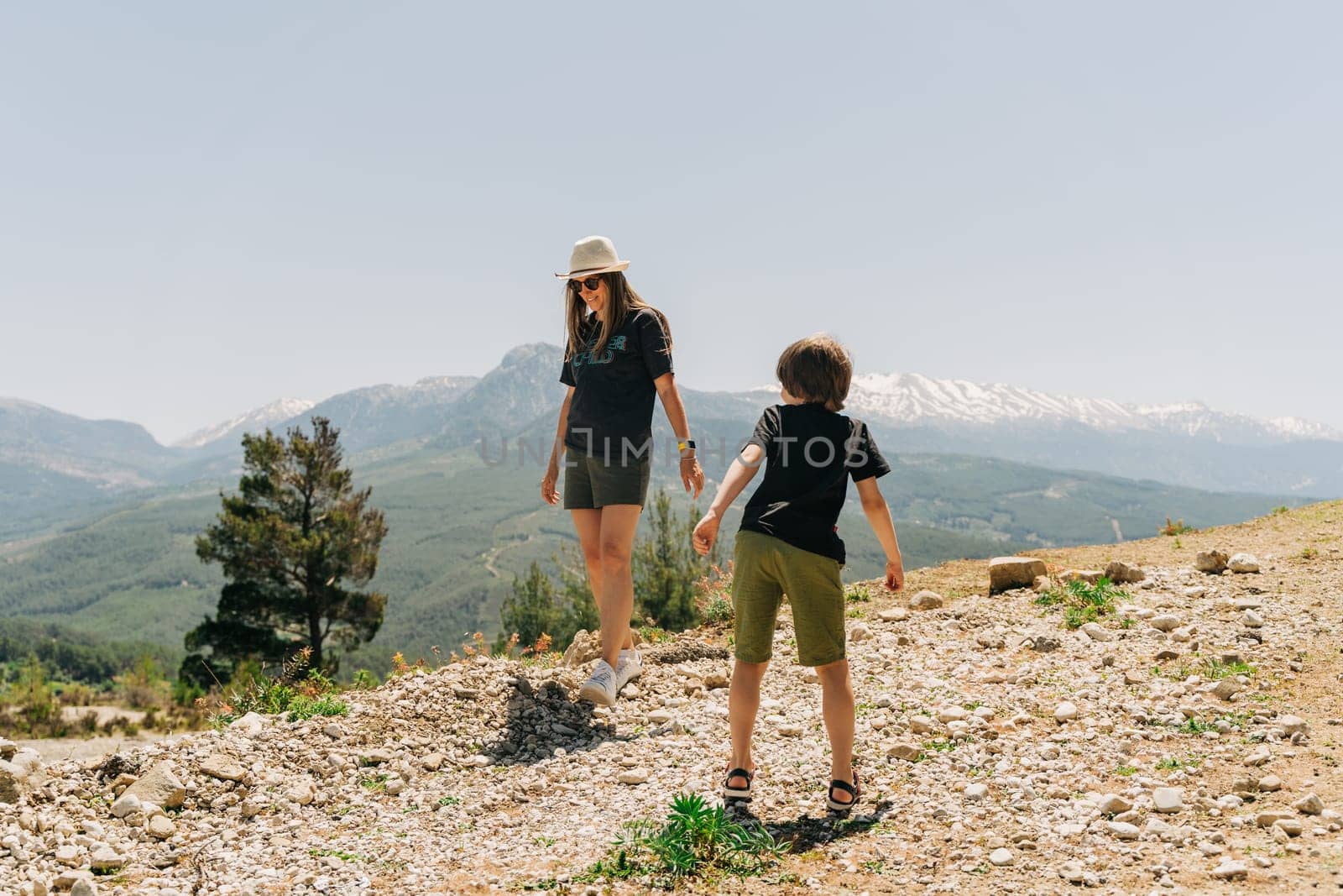 Young mom and her son standing on Mountain View. Child kid boy having fun with mother on mountains hiking.