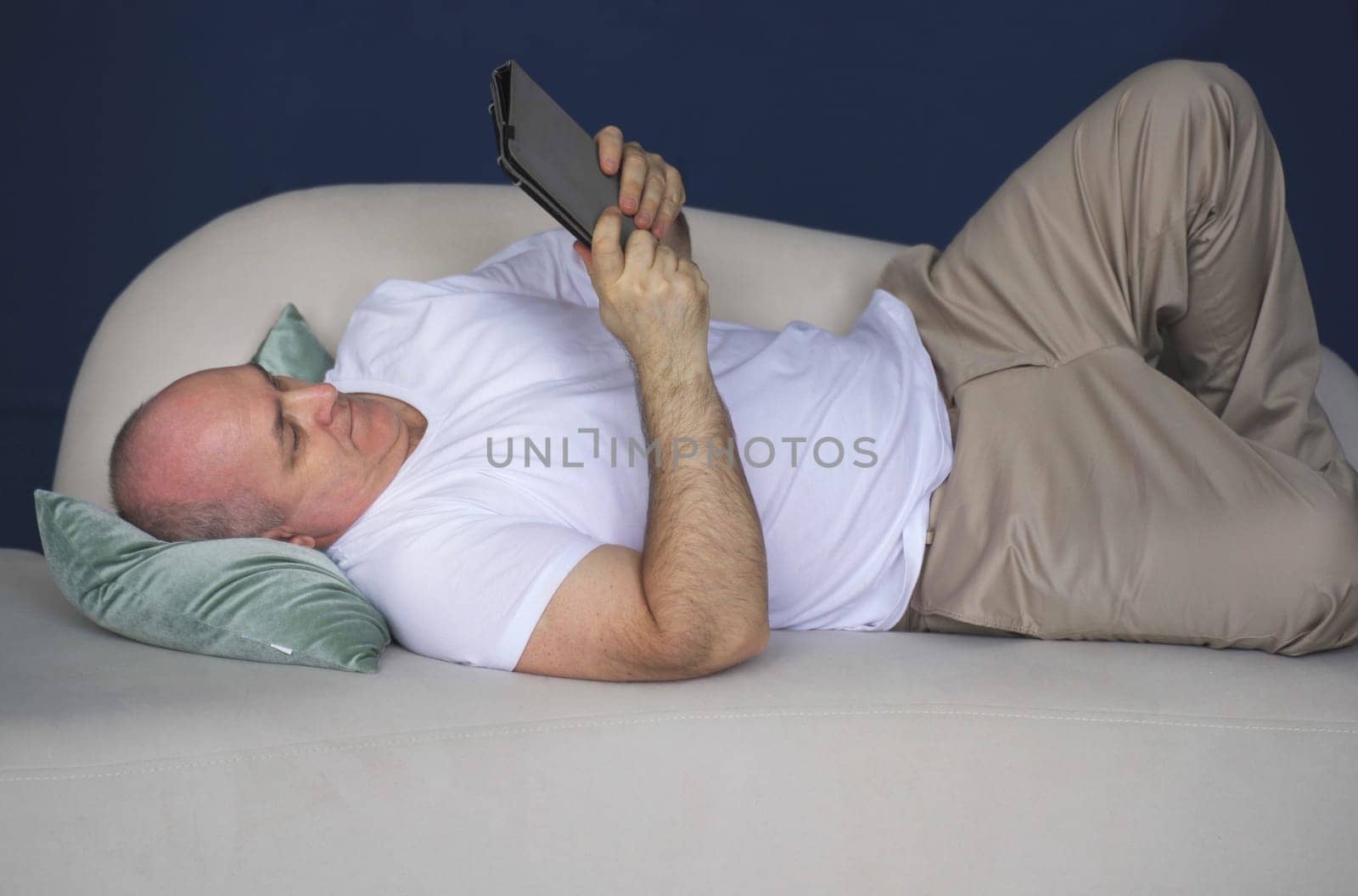 A middle-aged man lies on the couch and makes notes in a notebook. by Sd28DimoN_1976