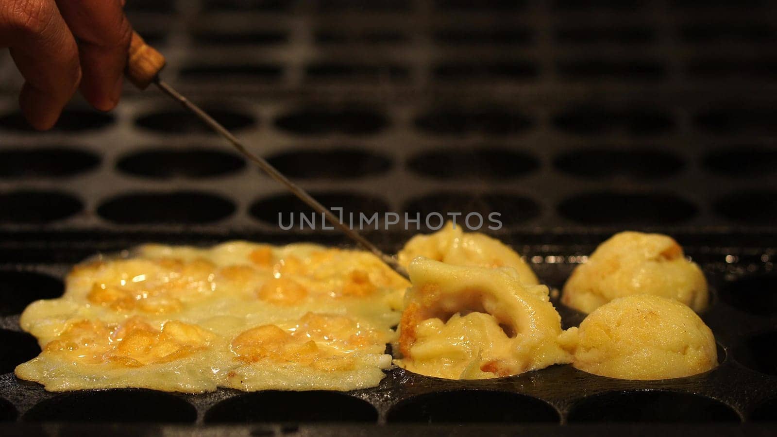 The cooking of Takoyaki. The popular Japanese street food that consists of small, ball-shaped snacks made of batter and filled with small pieces of octopus and other ingredients.