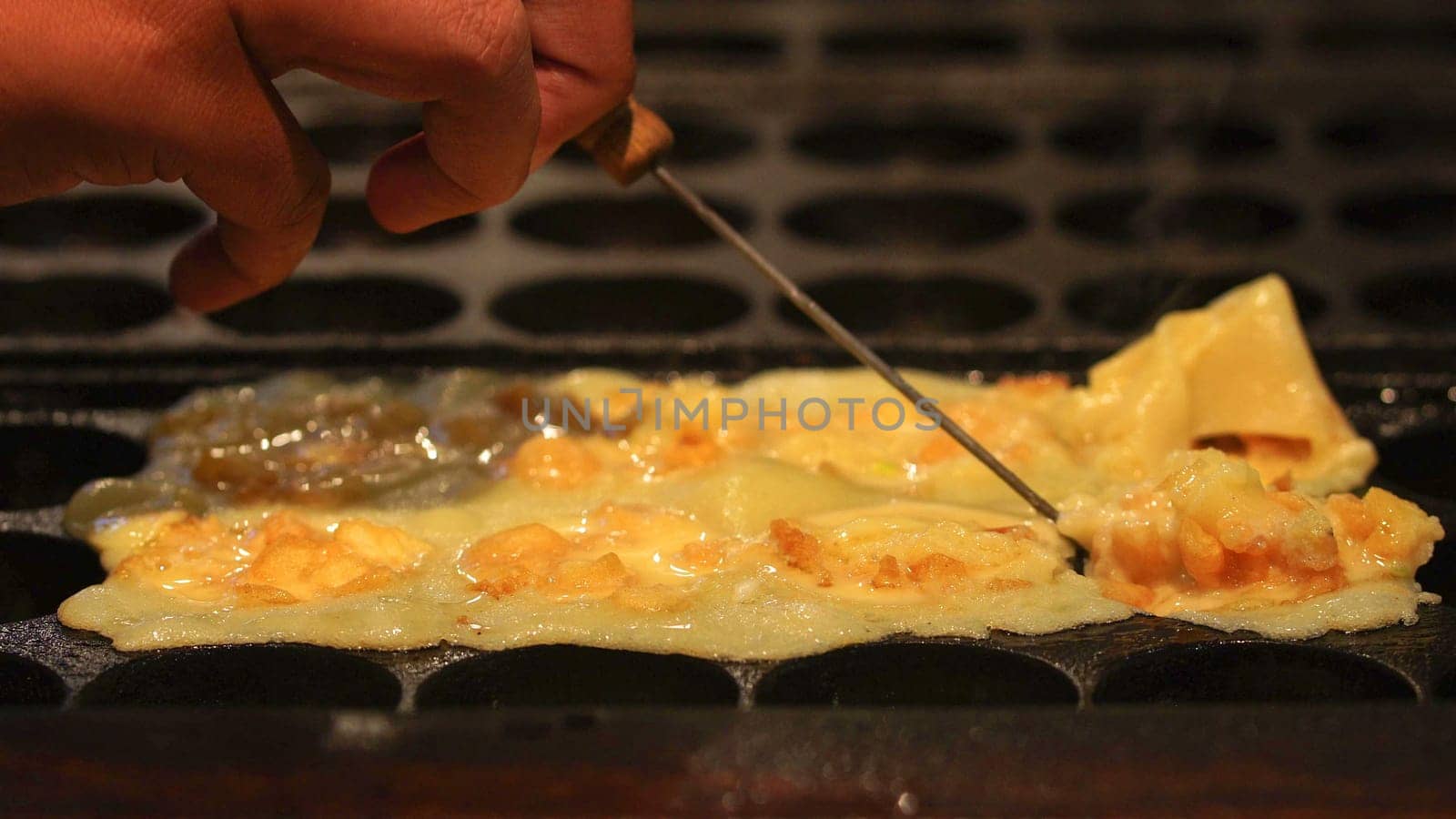 The cooking of Takoyaki. The popular Japanese street food that consists of small, ball-shaped snacks made of batter and filled with small pieces of octopus and other ingredients.