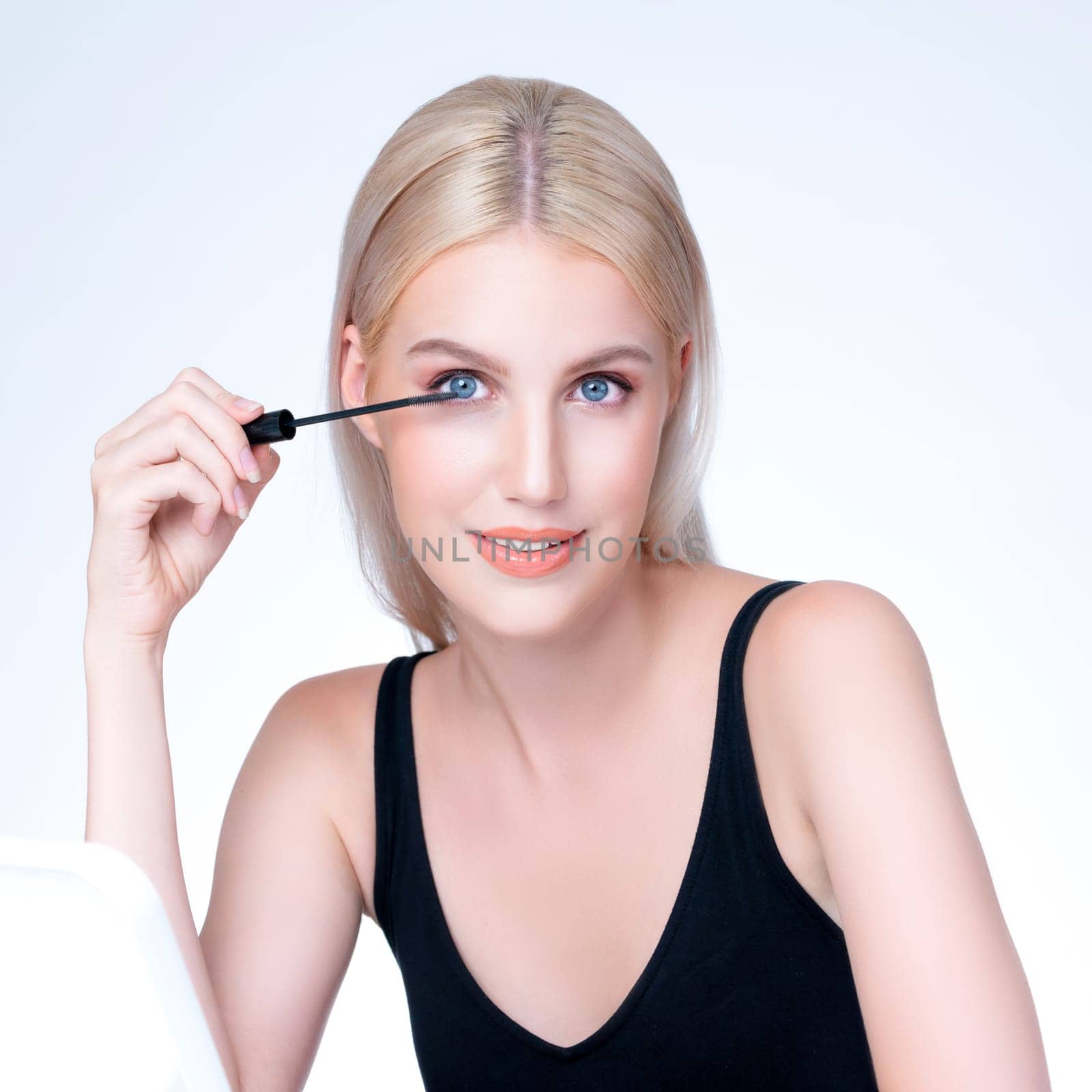 Closeup personable beautiful woman putting alluring black mascara eyelashes. by biancoblue