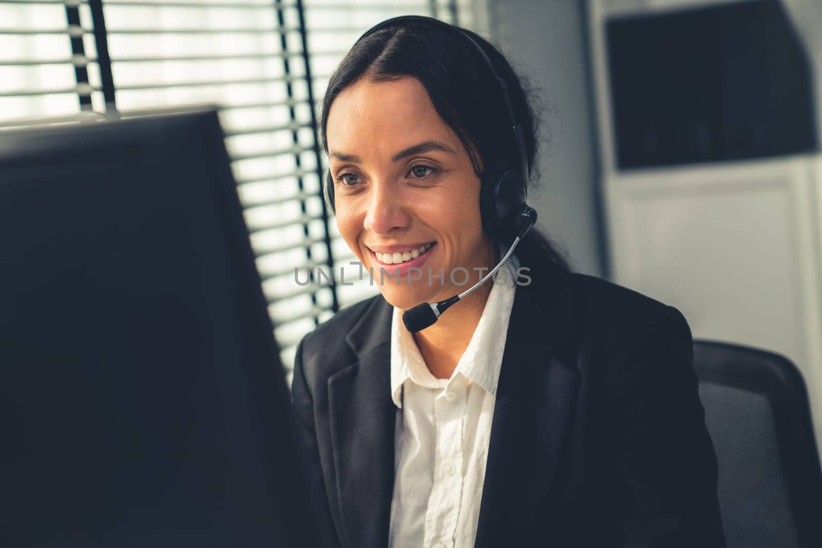 Competent female operator working on computer and talking with clients. Concept relevant to both call centers and customer service offices.