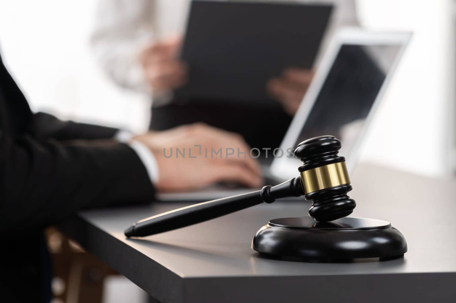 Focus gavel hammer for righteous and equality judgment with blur background of lawyer colleagues or legal team working with laptop, drafting legal documents for litigation at law firm. Equilibrium