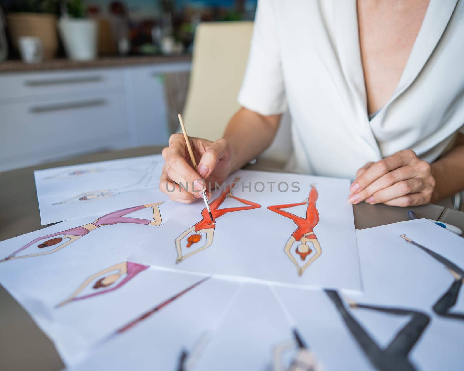 Faceless woman draws watercolor sketches of sportswear. Close-up of the hands of a fashion designer. by mrwed54