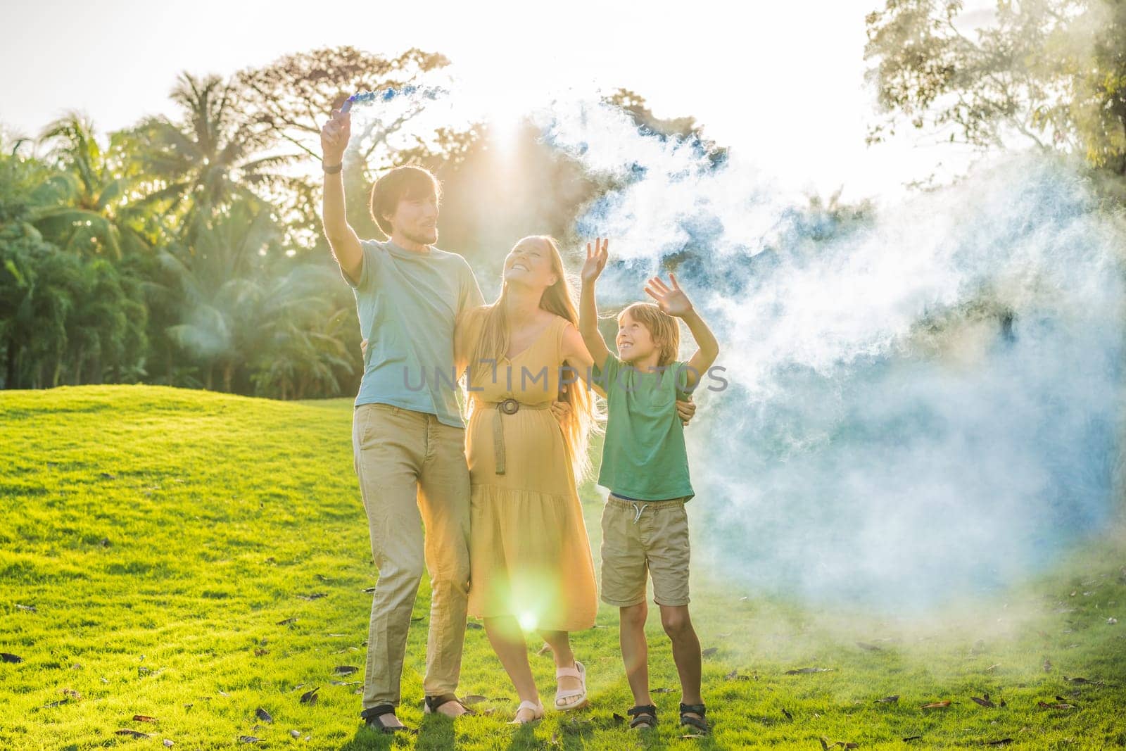 Pregnant mom, dad and son at the gender party on the golf course release blue smoke. Gender reveal announcement on the golf course. Loving family expecting baby boy. Happy moments.