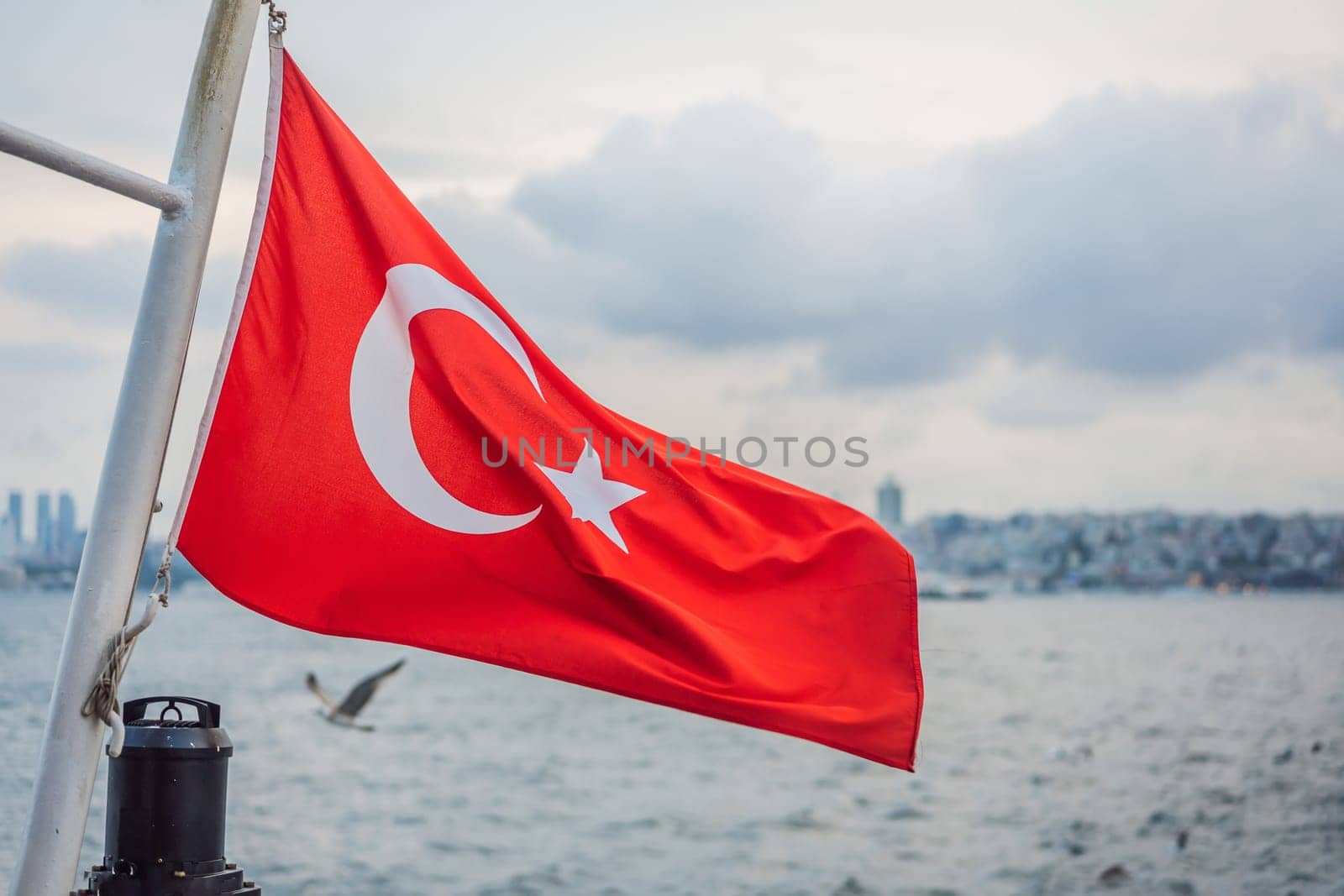 Turkish flag flying in the wind against the background of the sea and the coast.