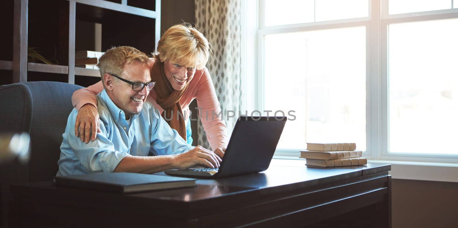 We have more than enough money for retirement. a mature woman keeping her husband company while he works from home. by YuriArcurs