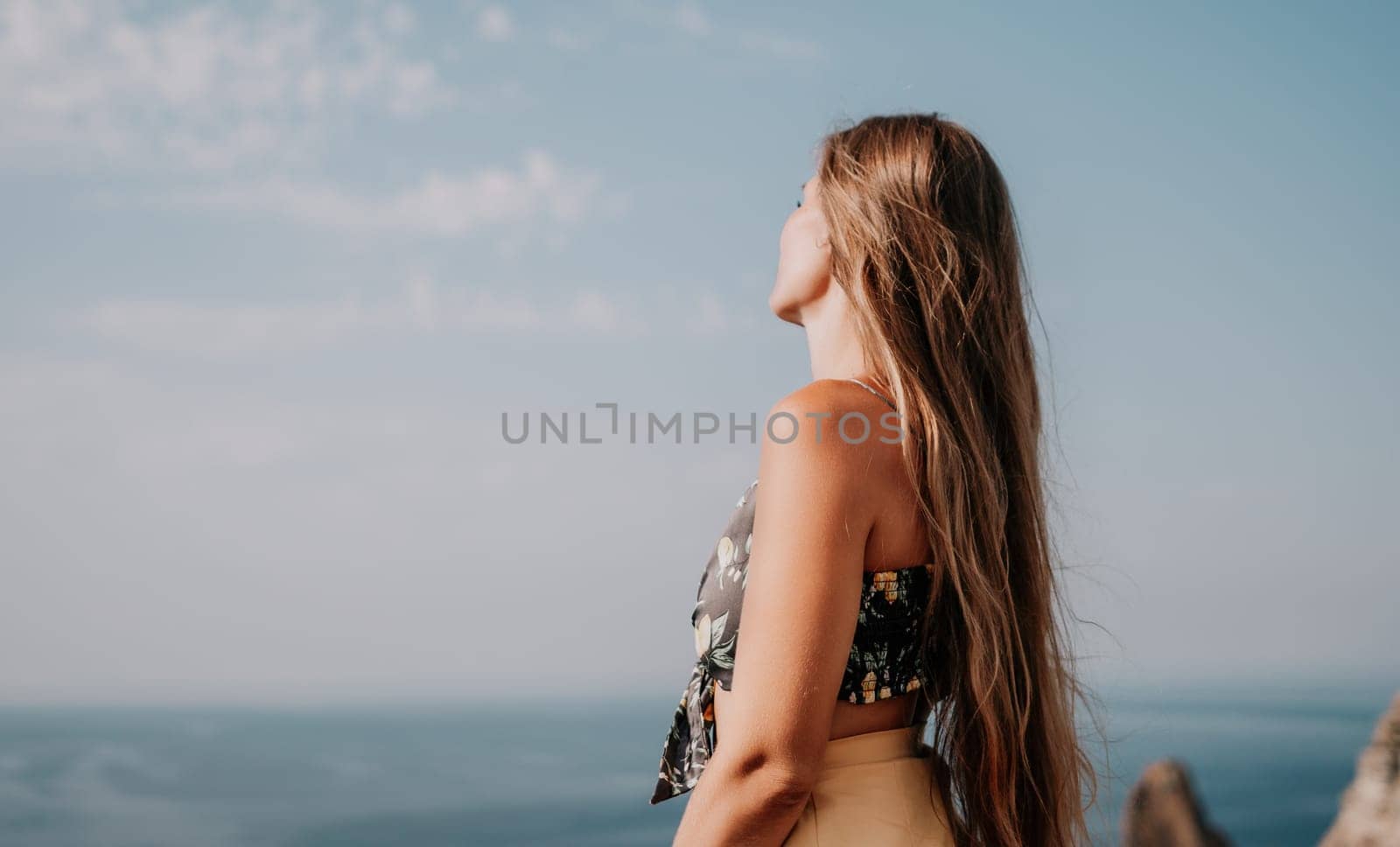 Woman travel sea. Happy tourist taking picture outdoors for memories. Woman traveler looks at the edge of the cliff on the sea bay of mountains, sharing travel adventure journey.