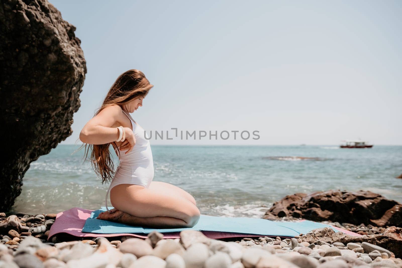Woman sea fitness. Happy woman with long hair, fitness instructor in white bikini doing stretching and pilates on yoga mat near the sea. Female fitness yoga routine concept. Healthy lifestyle. by panophotograph