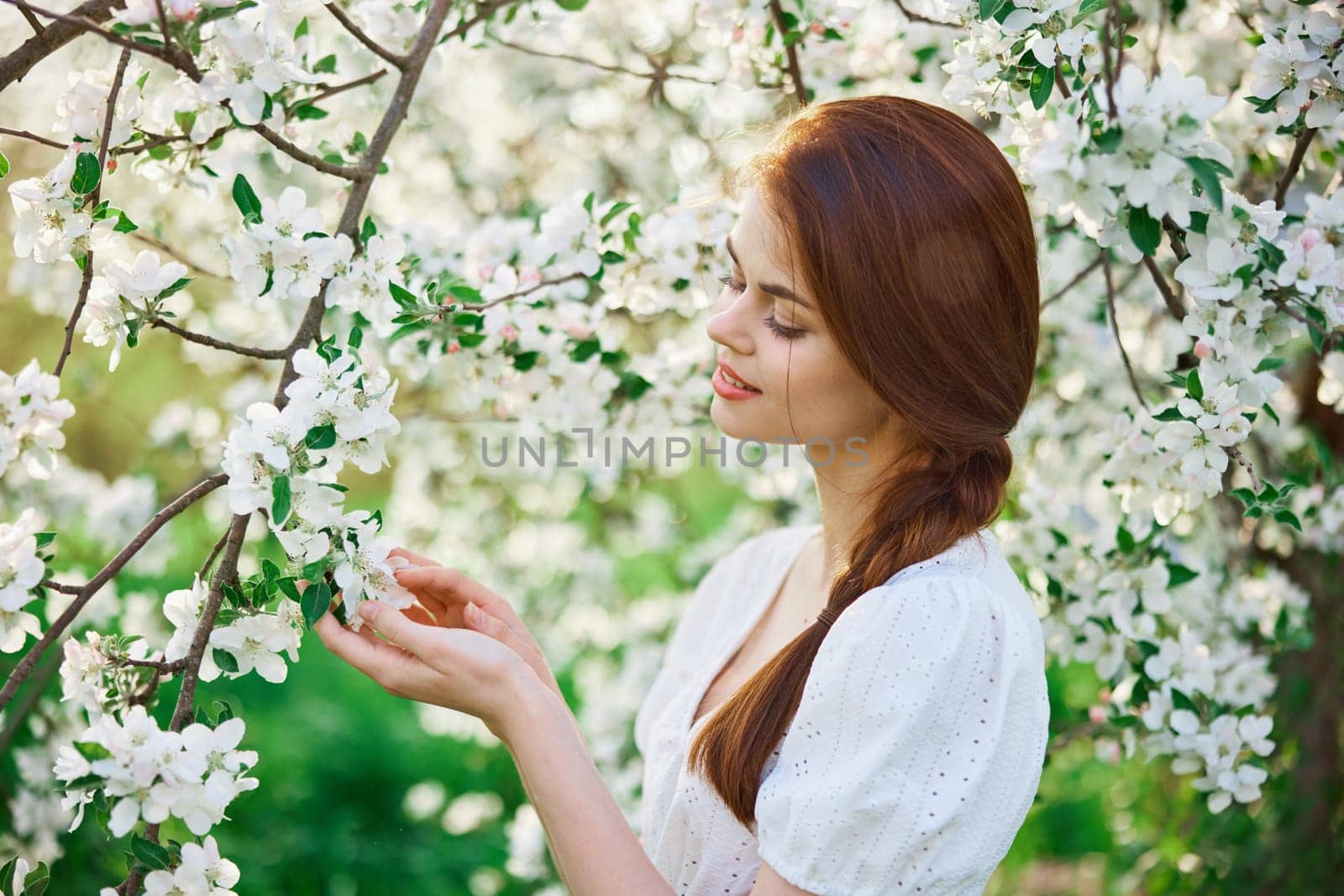 beautiful, cute woman touching flowers on a tree in the garden. High quality photo