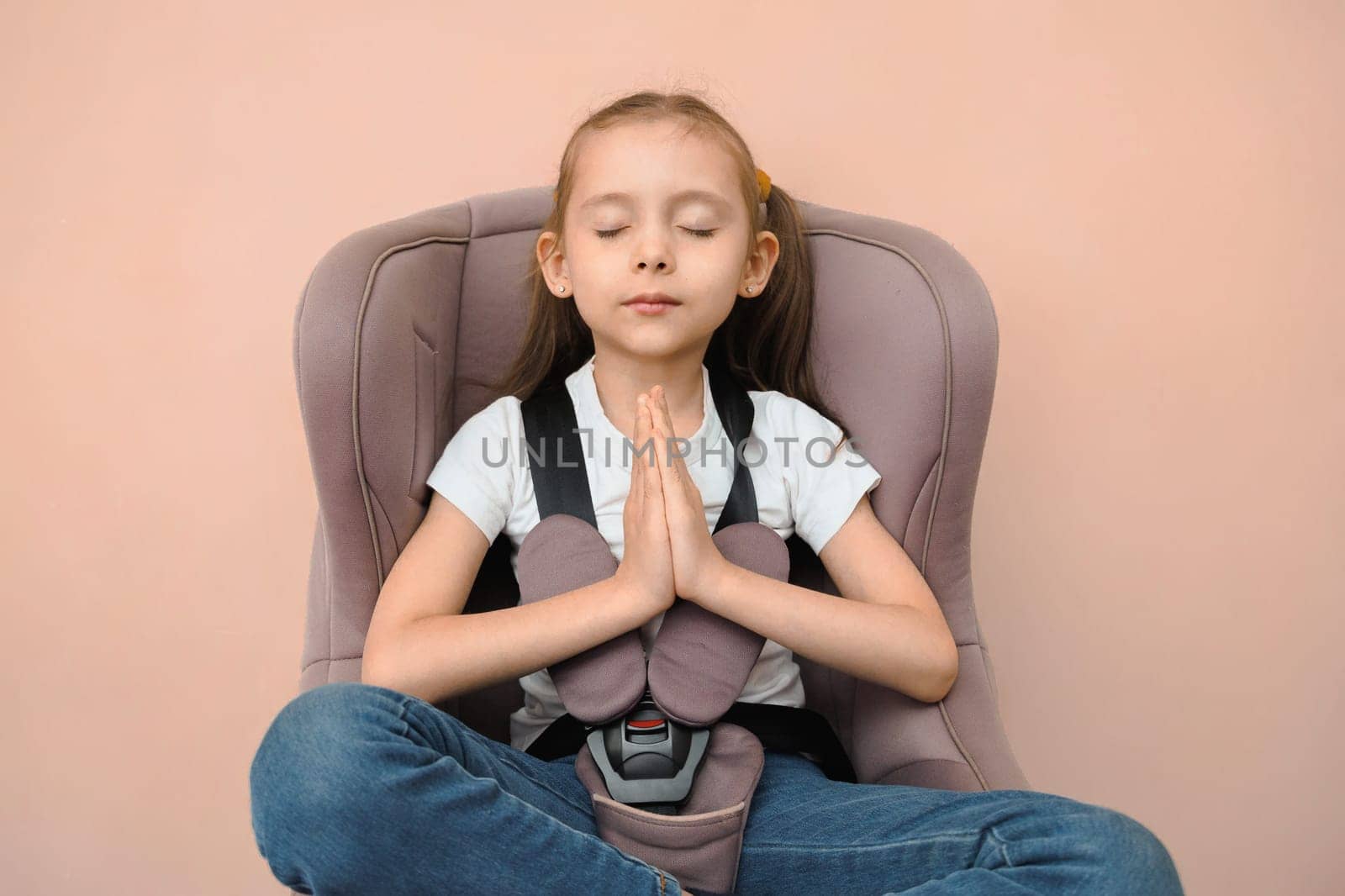 Funny happy caucasian girl of primary school age feels calm and safe in a car seat.