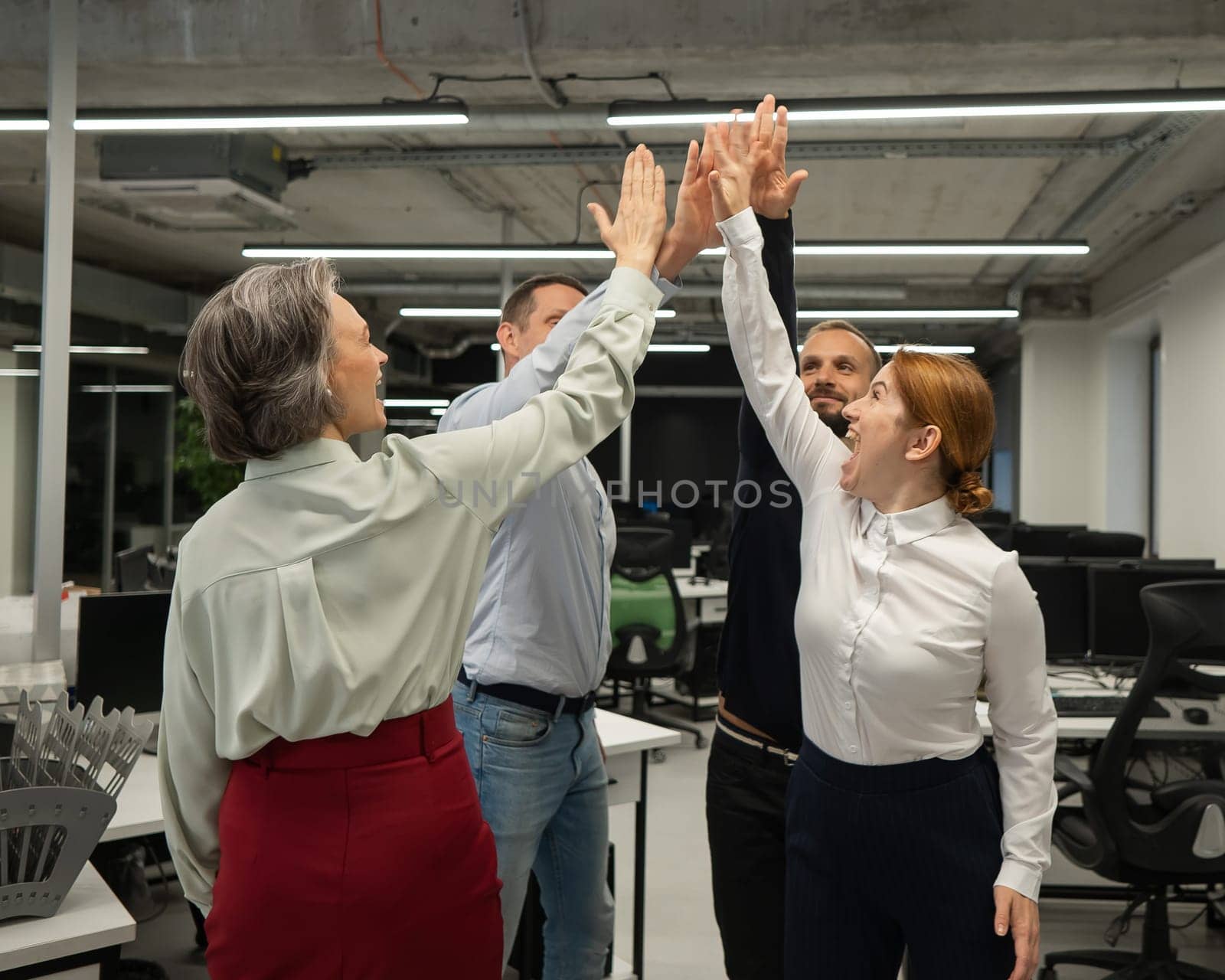 Four co-workers give a high five in the office