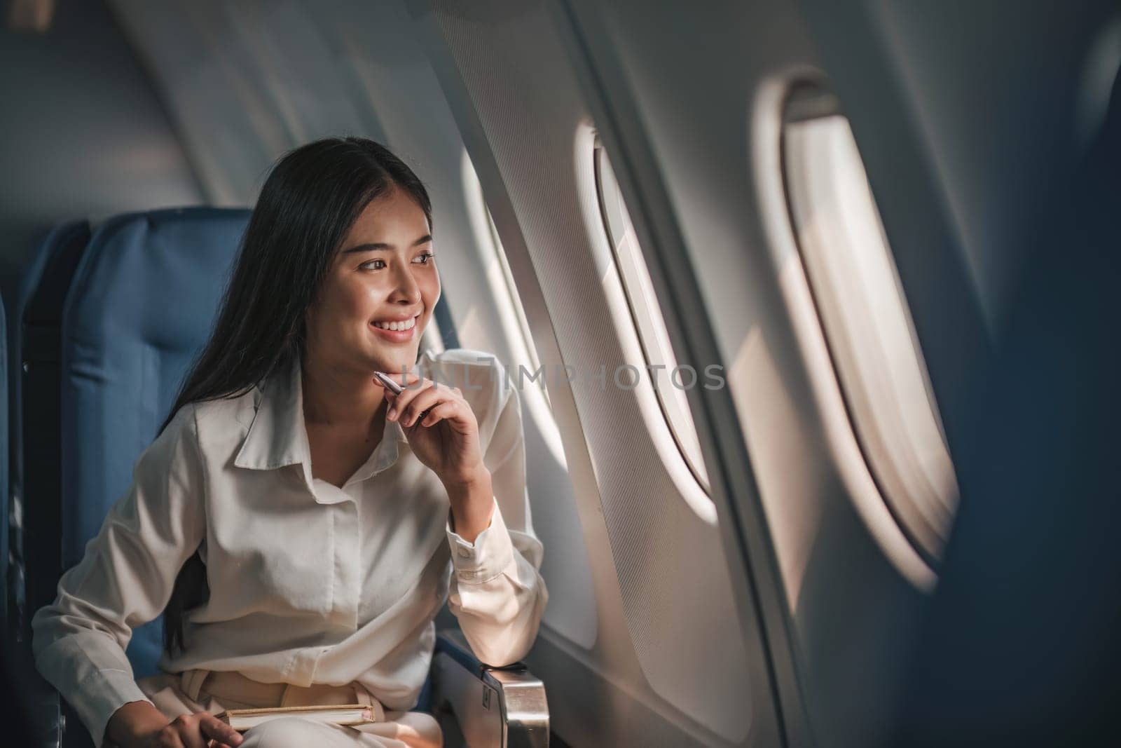 Young, beautiful girl the passenger seat in a charter plane or business jet near the porthole and smiles..