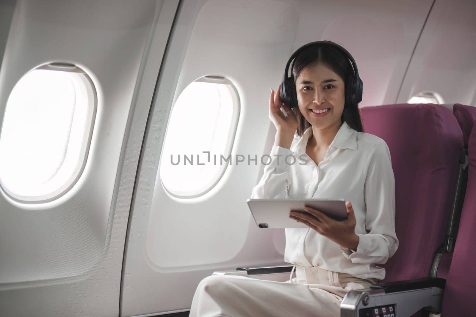 Asian young woman using tablet sitting near windows at first class on airplane during flight,Traveling and Business concept..