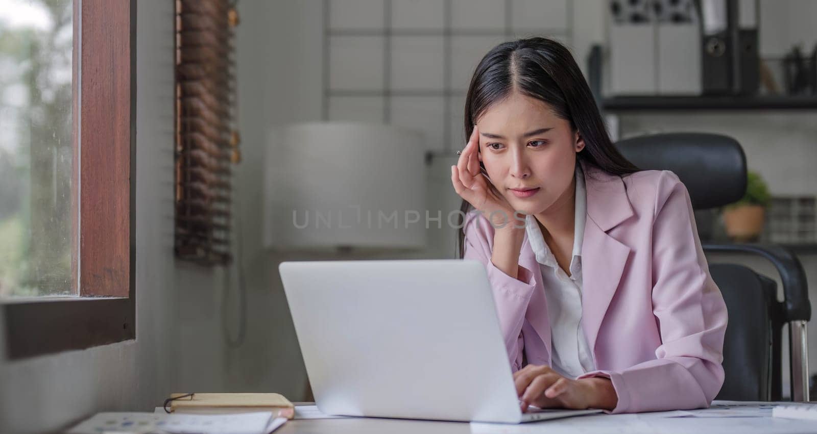 asian woman thinking hard concerned about online problem solution looking at laptop screen, worried serious asian businesswoman focused on solving difficult work computer task. by wichayada