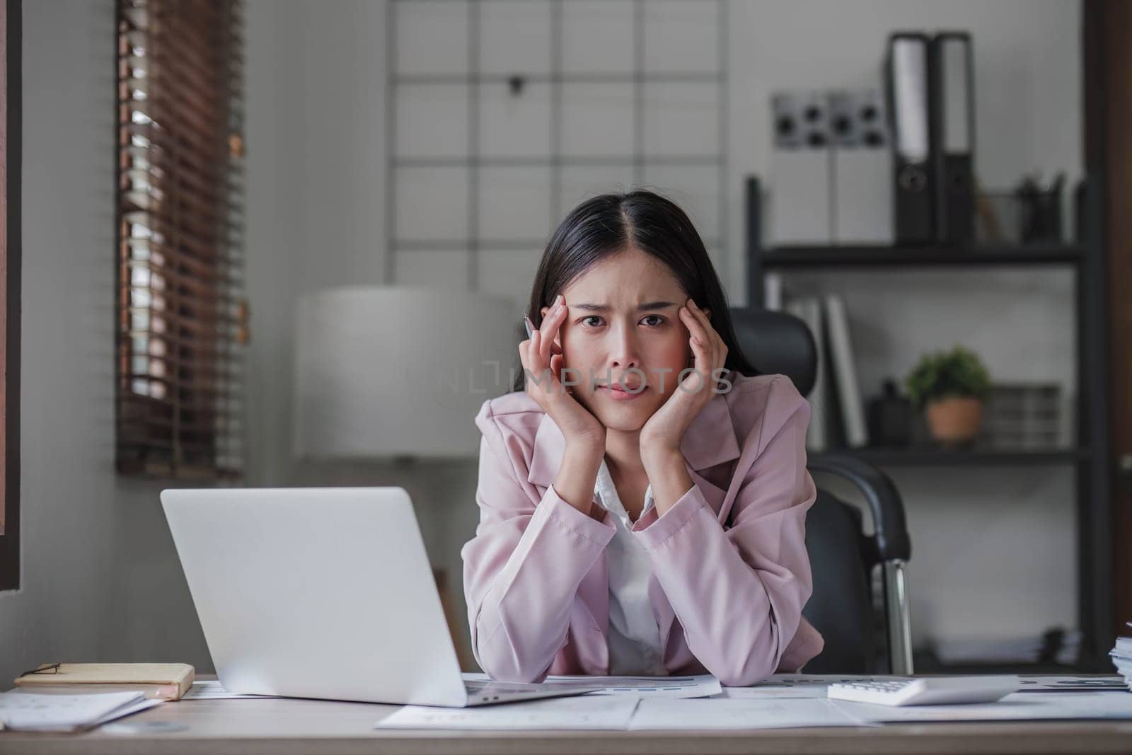 asian woman thinking hard concerned about online problem solution looking at laptop screen, worried serious asian businesswoman focused on solving difficult work computer task. by wichayada