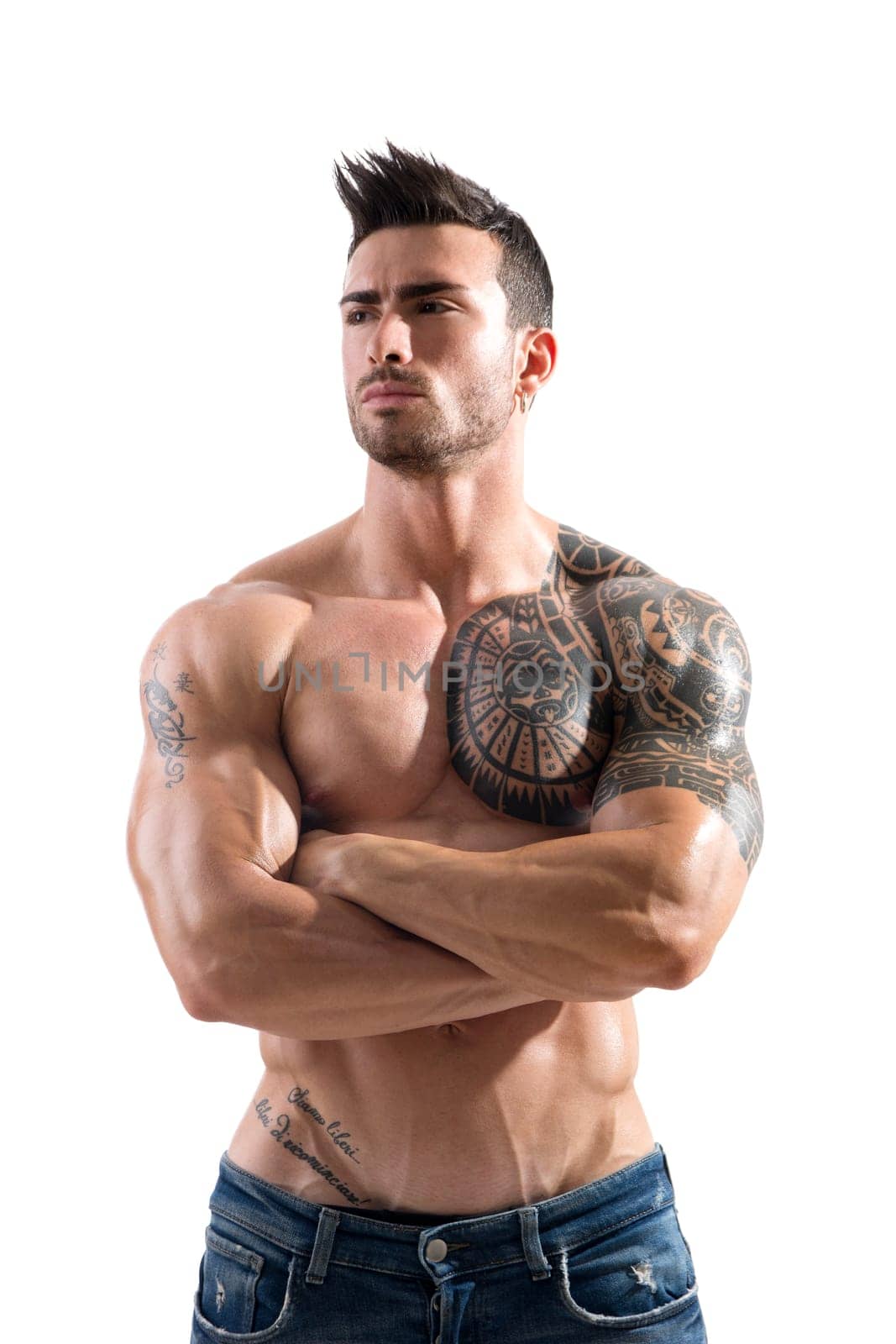 Handsome shirtless athletic man in jeans, with arms crossed on muscular chest, looking away in studio shot, isolated on white background