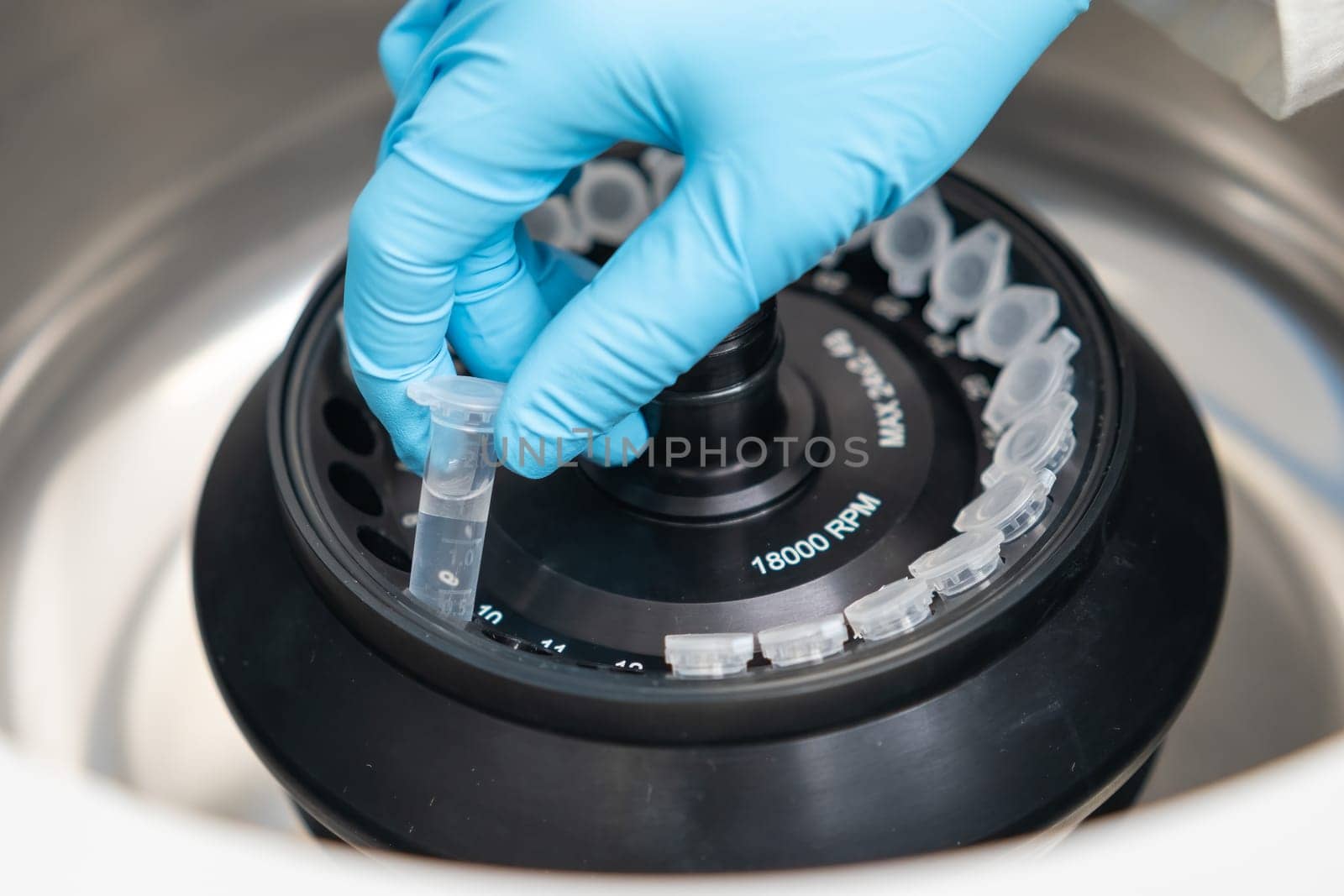 Scientist puts microcentrifuge tubes into centrifuge for phase separation. Metabolomic and lipidomic analysis in the analytical chemistry laboratory.